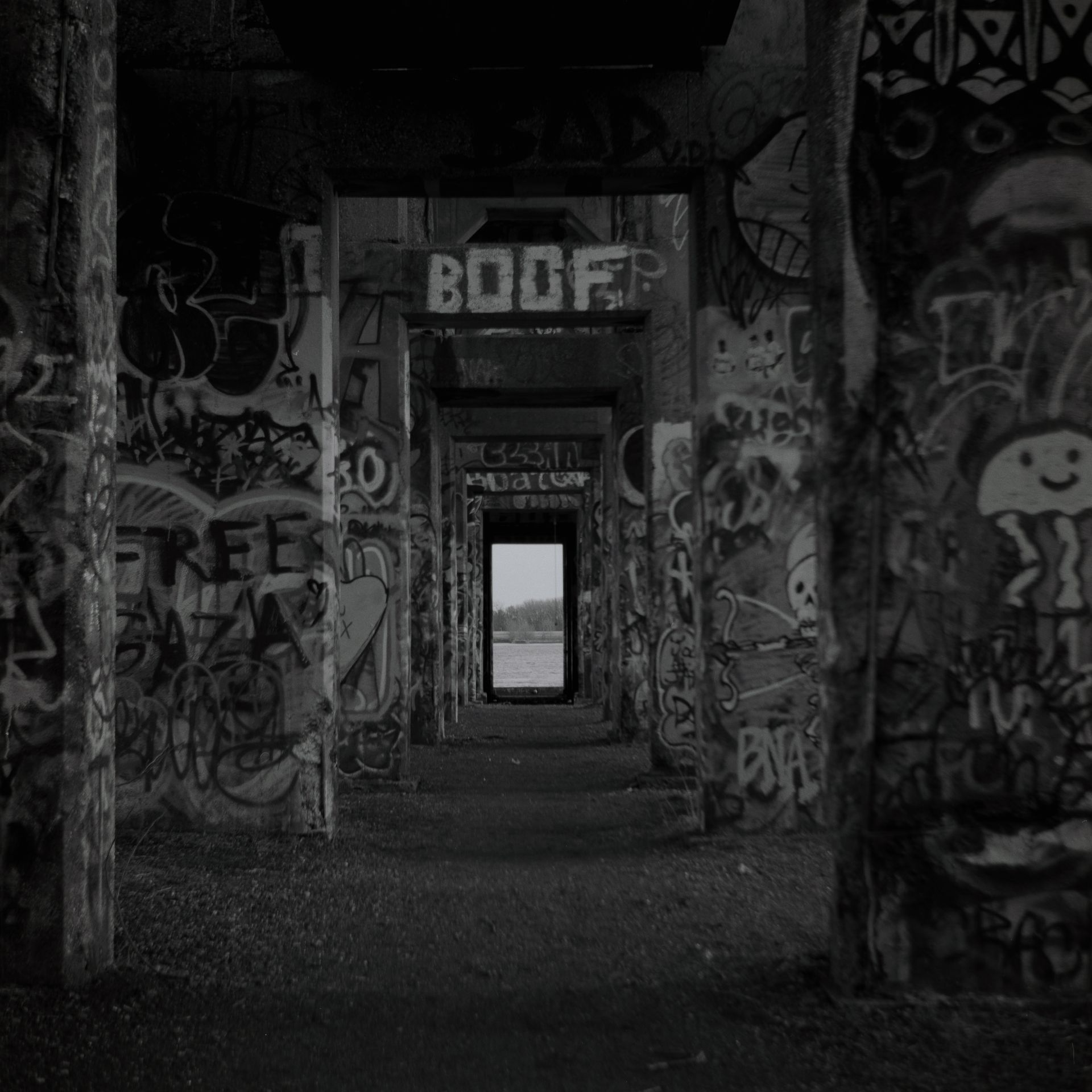A black and white photo of a hallway covered in graffiti.