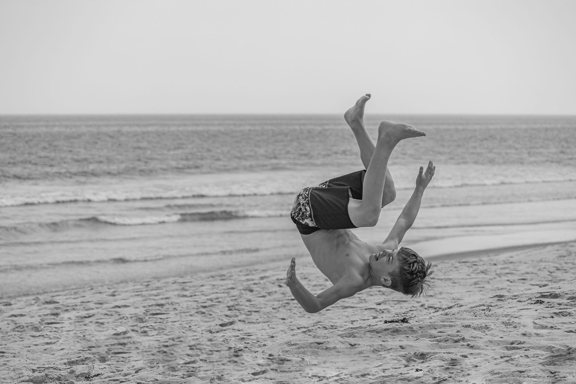A man is doing a handstand on the beach.