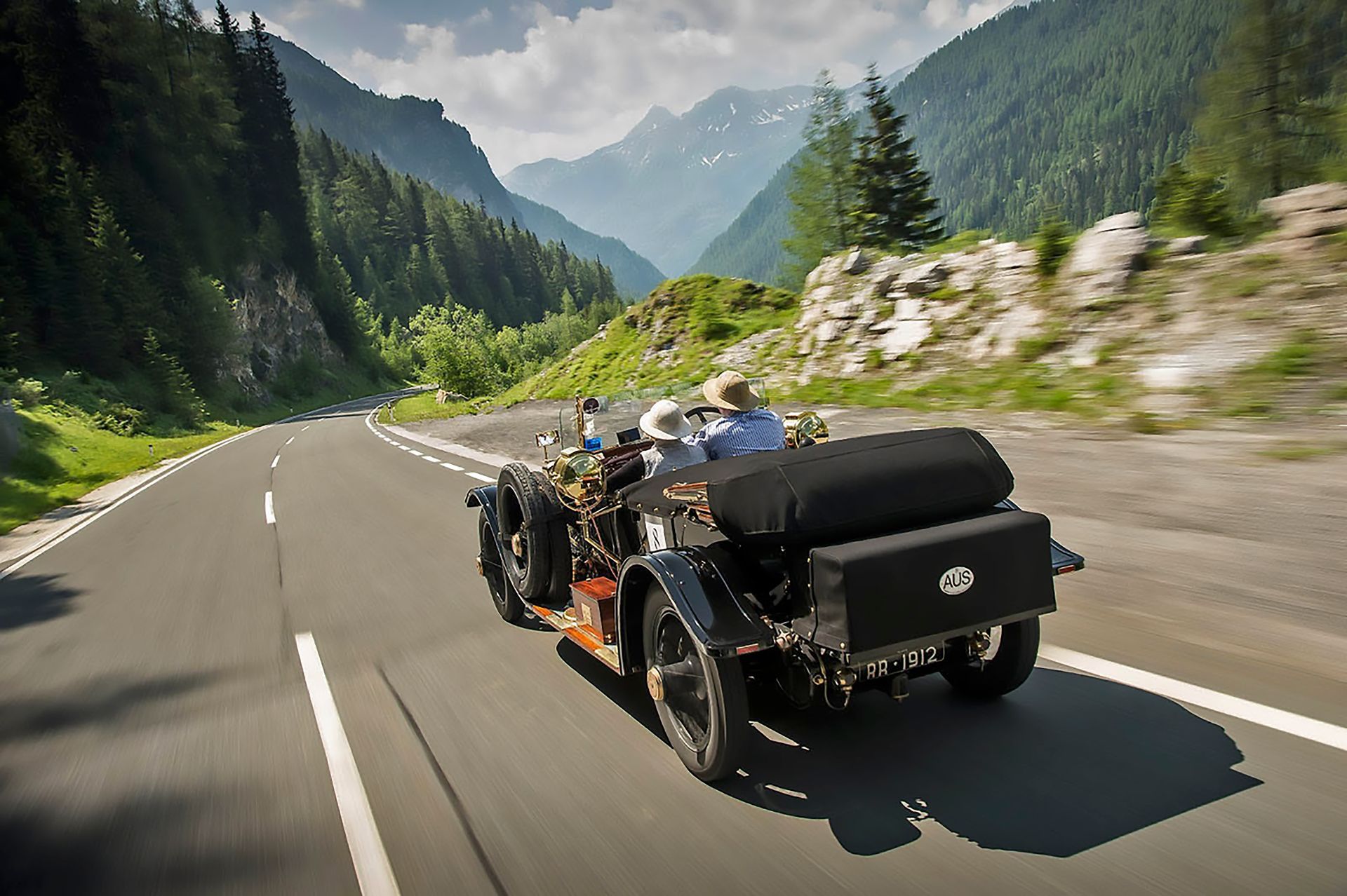An old car is driving down a mountain road