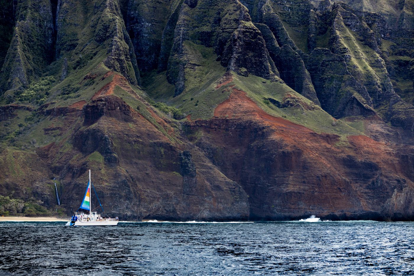 A sailboat is floating in the water near a mountain.