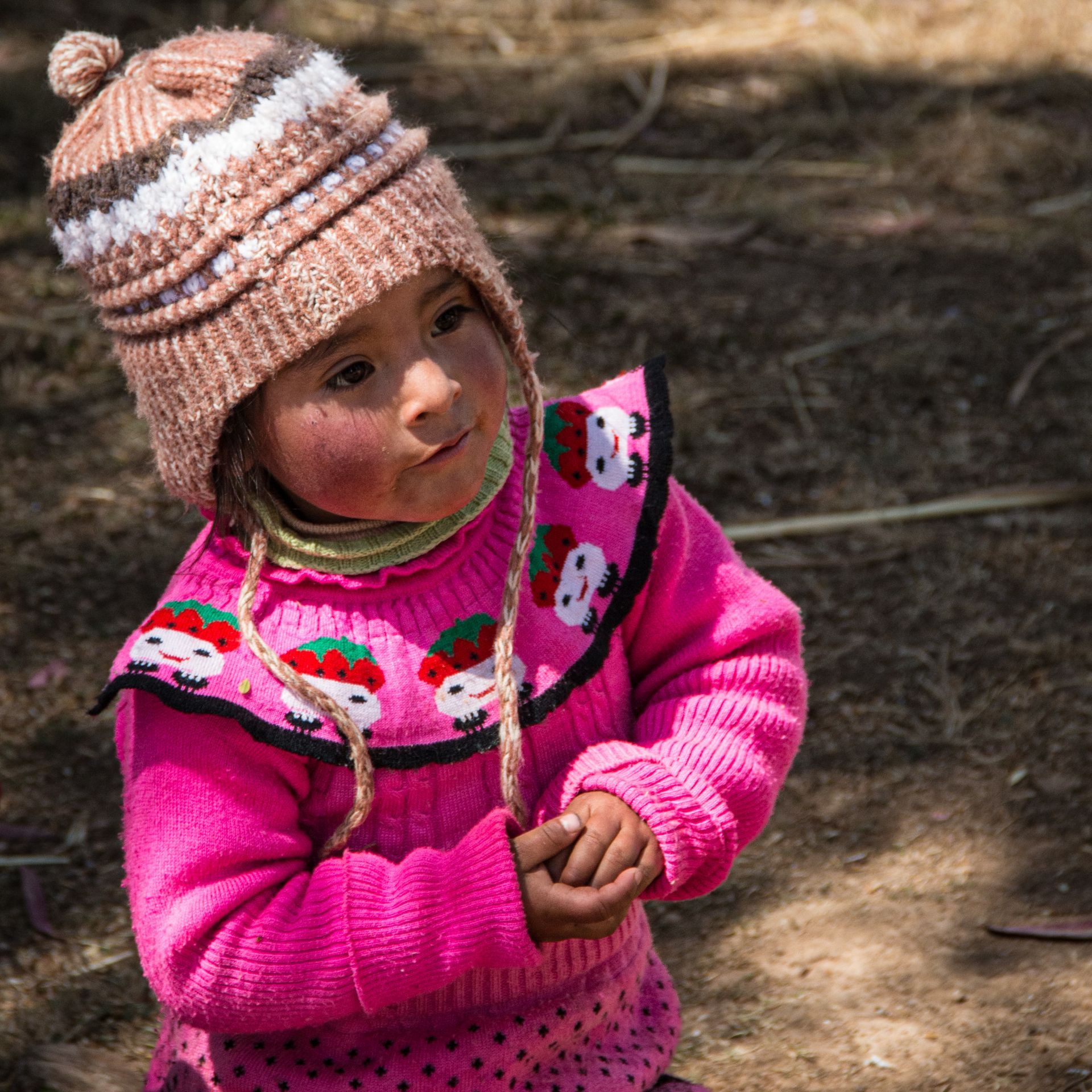 A little girl wearing a pink sweater and hat
