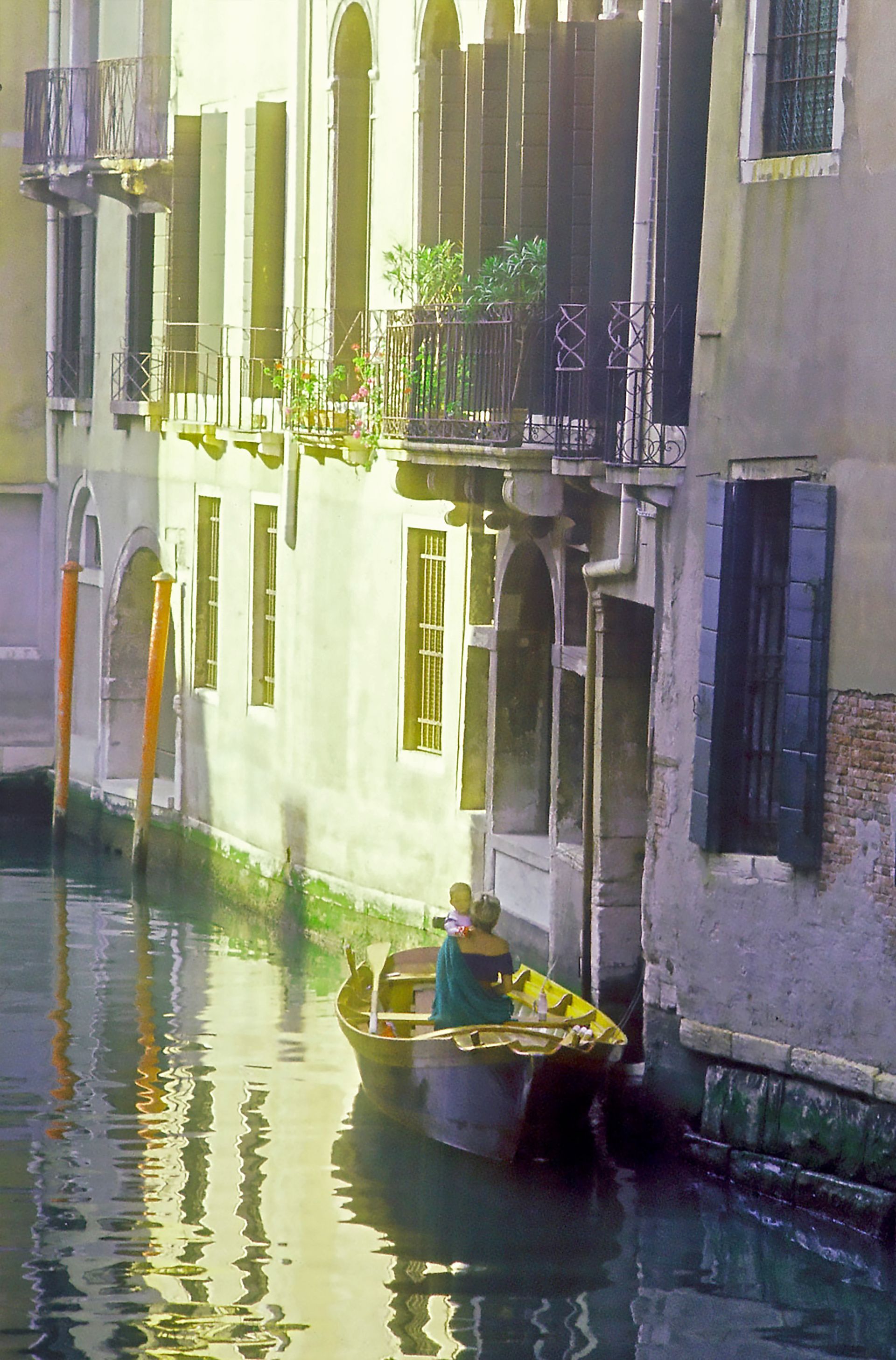A man in a yellow boat is going down a canal