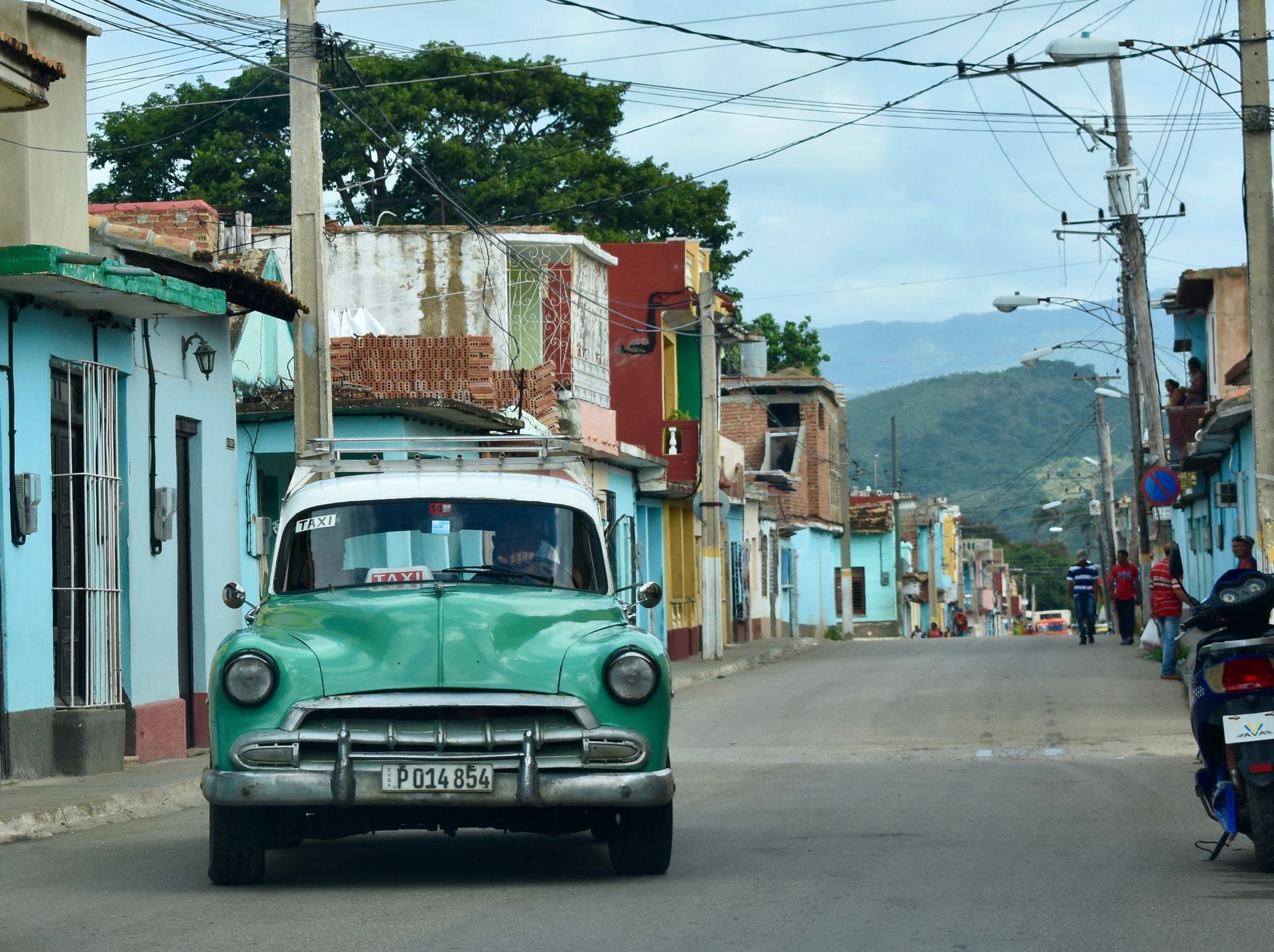 A green car is parked on the side of the road