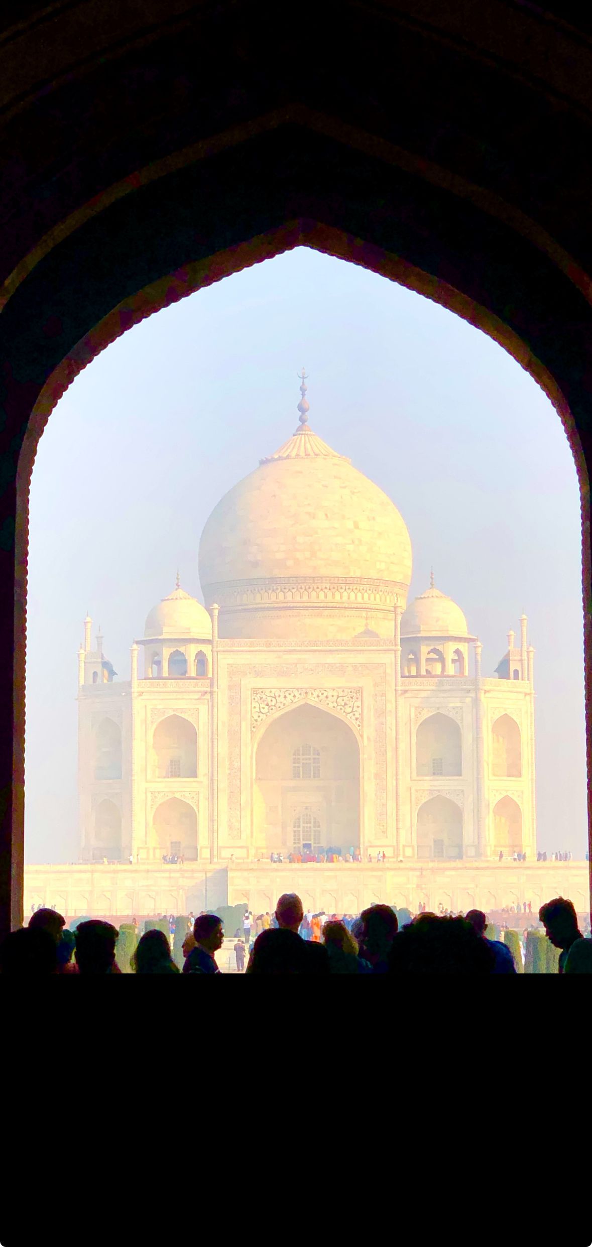 A group of people are looking at the taj mahal through an archway.