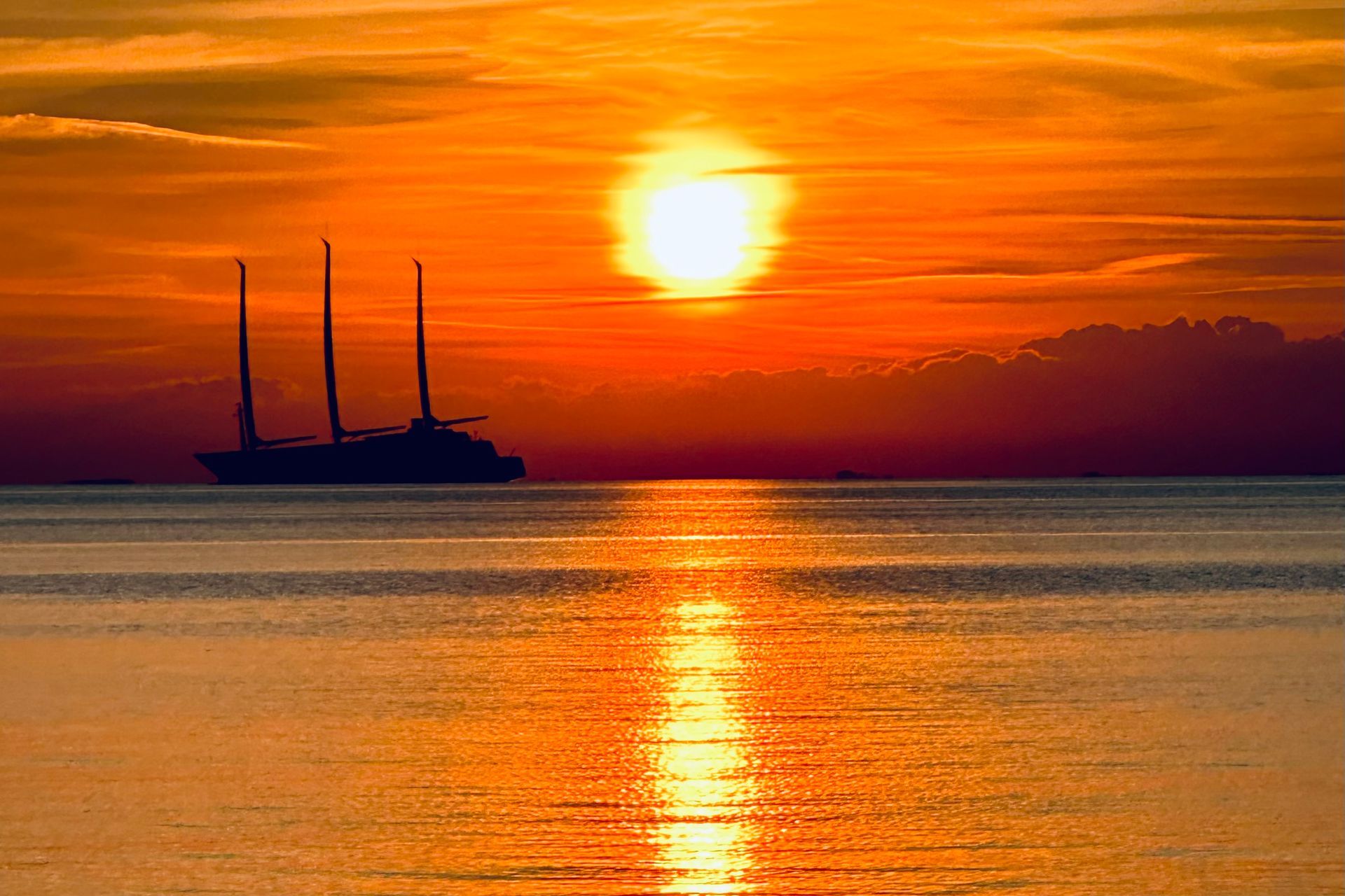 A boat is floating on top of a body of water at sunset.