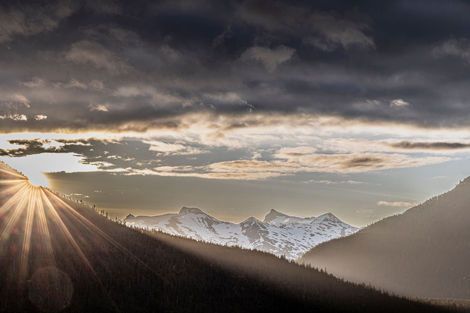The sun is shining through the clouds over the mountains.