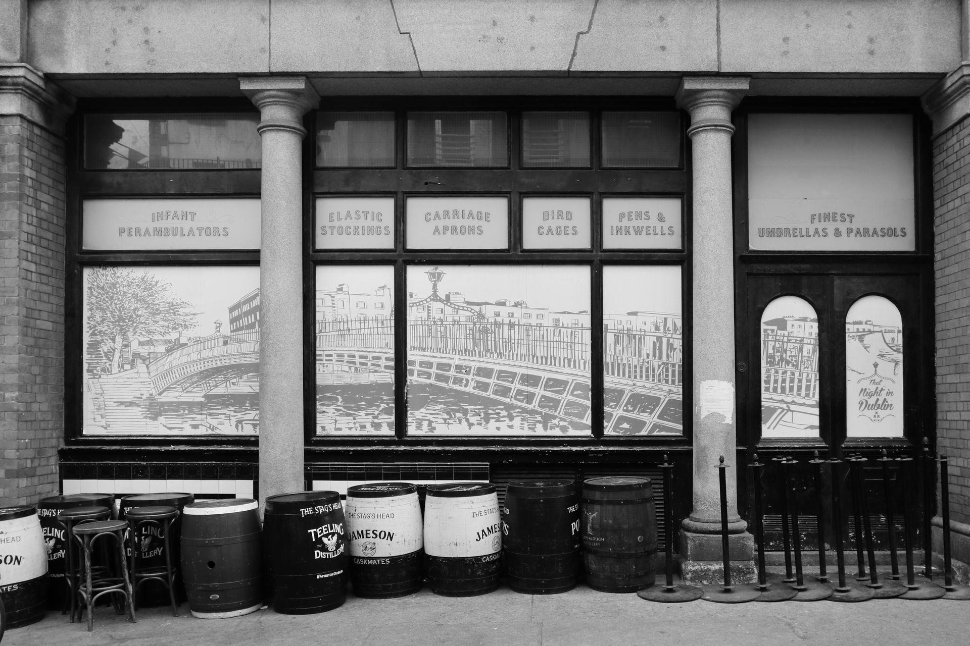 A black and white photo of a building with barrels in front of it
