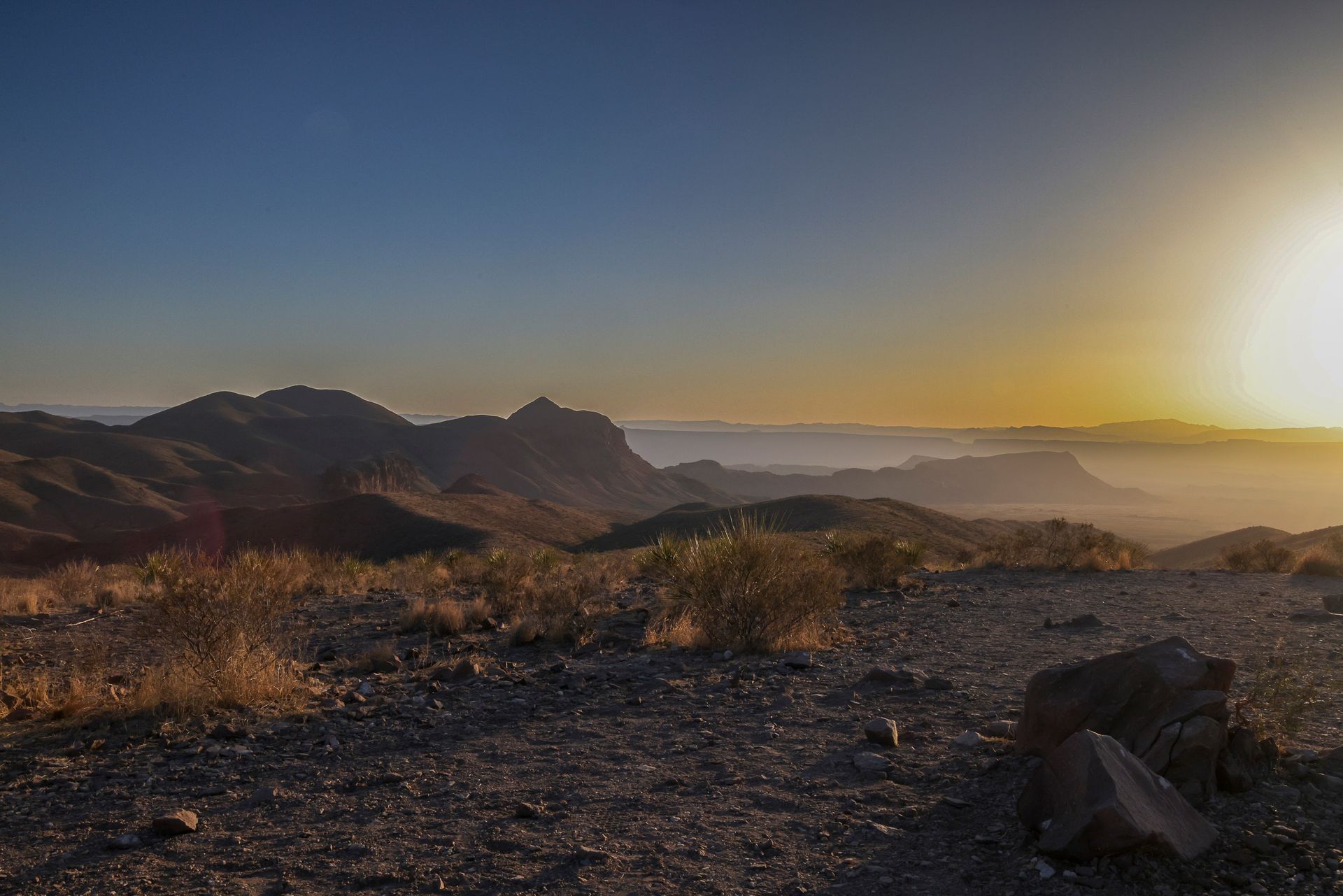 The sun is setting over the mountains in the desert.