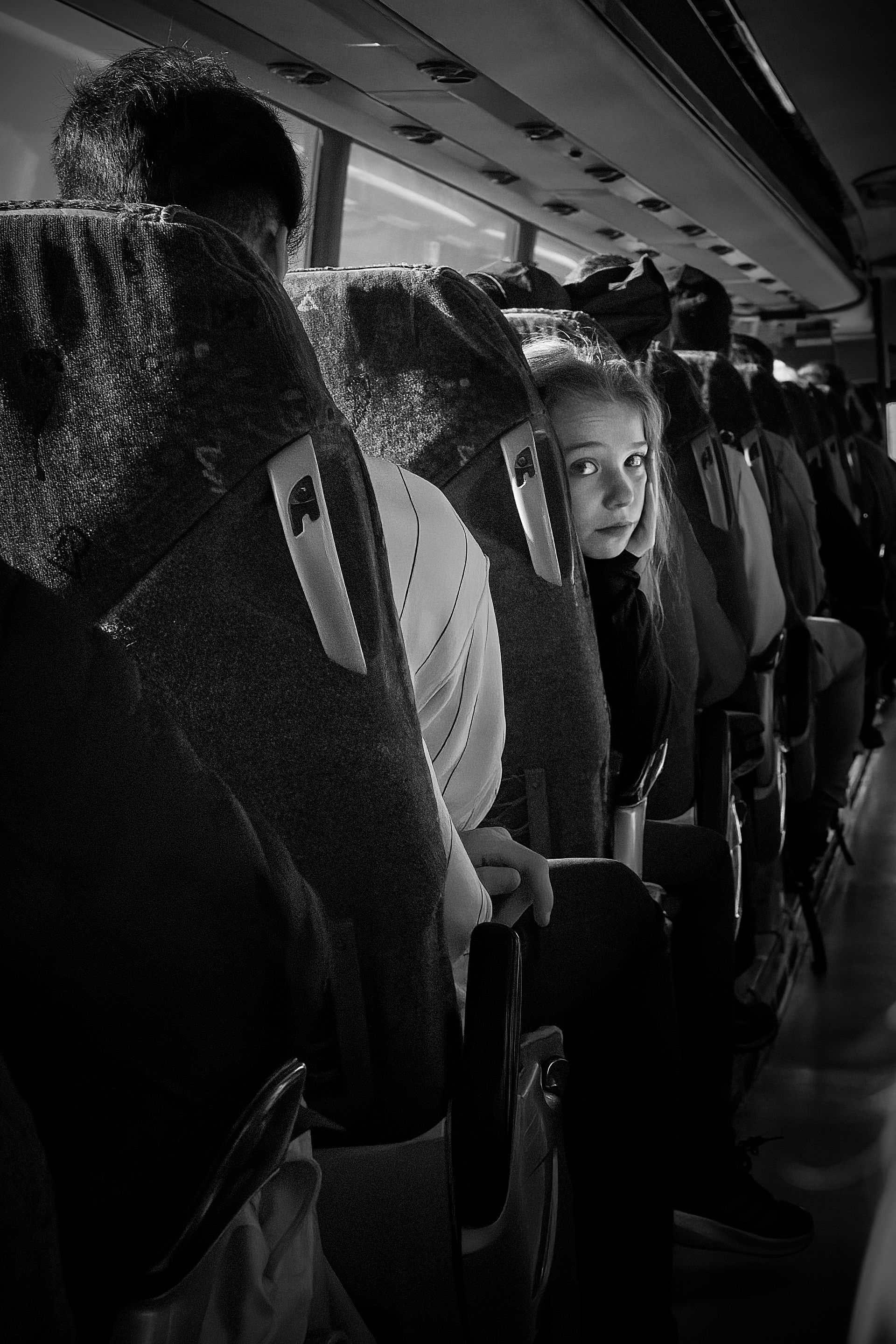 A black and white photo of people sitting on a bus.