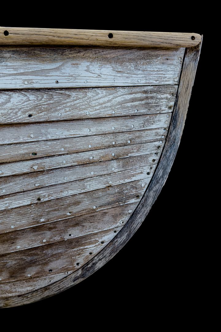 A close up of a wooden boat on a black background.