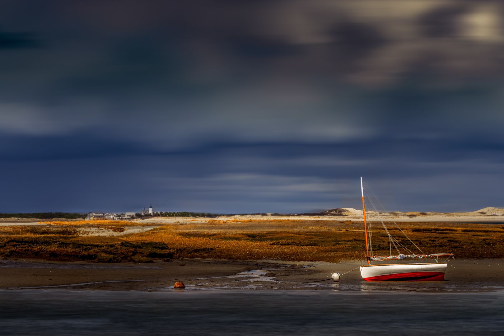 A boat is floating on top of a body of water on a cloudy day.
