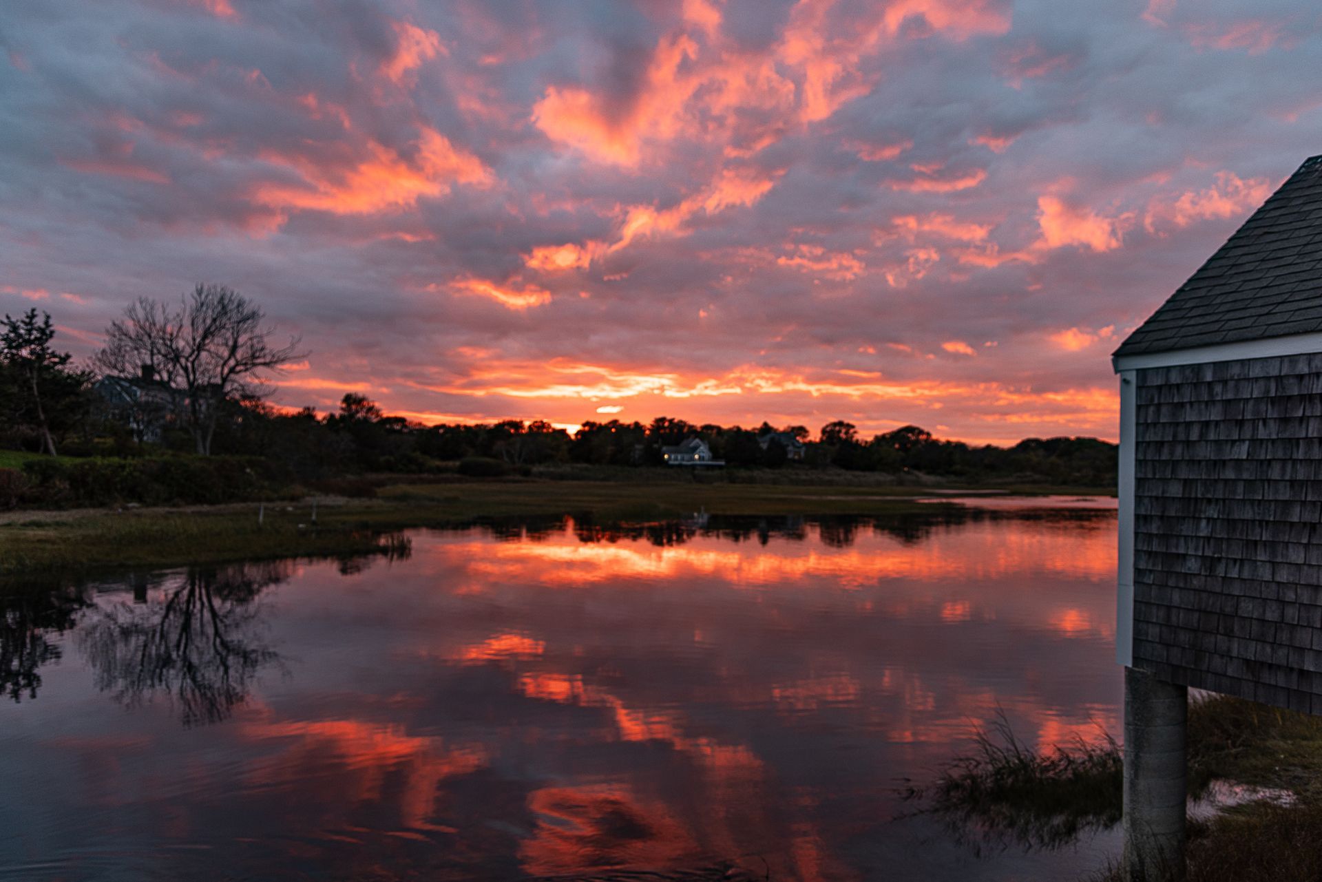 a sunset over a body of water with a house in the foreground .