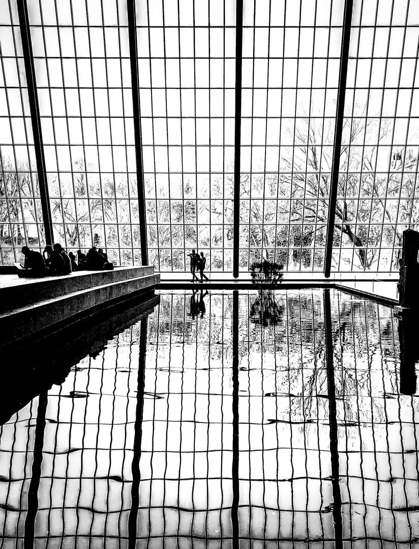 A black and white photo of a swimming pool in a building.