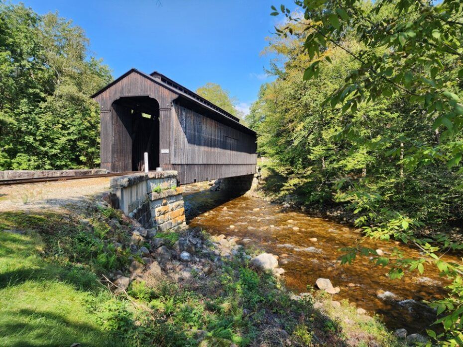 a covered bridge over a river in the woods