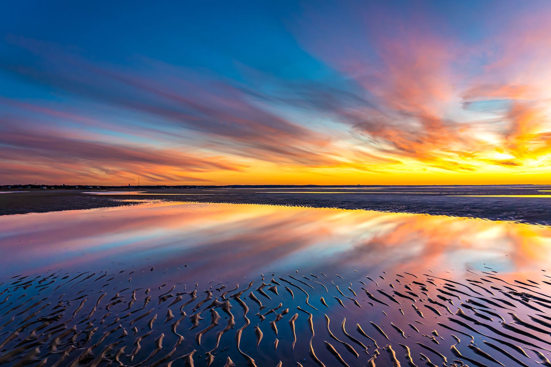 a sunset over a body of water with a reflection of the sky in the water .