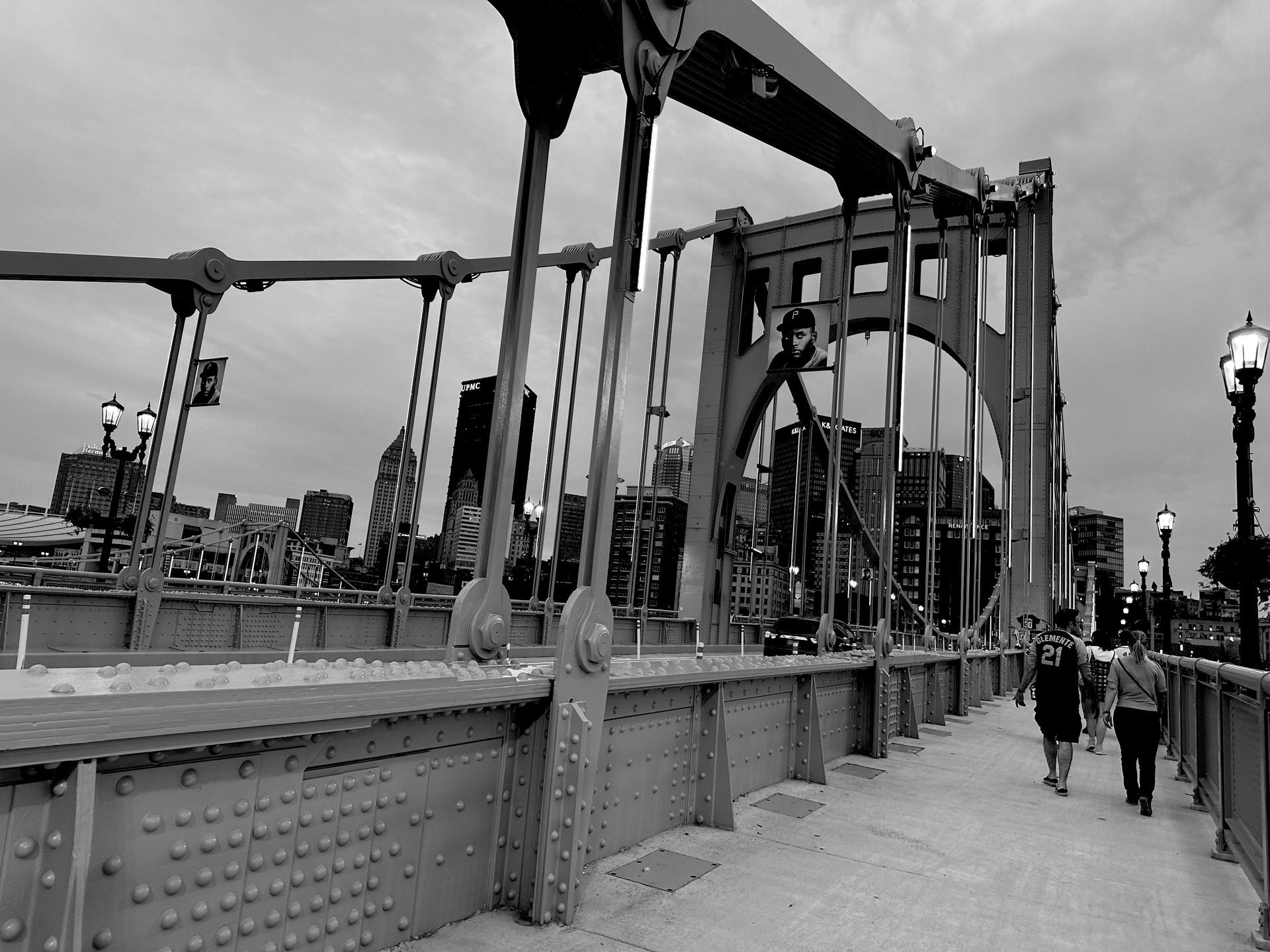 A black and white photo of people walking across a bridge