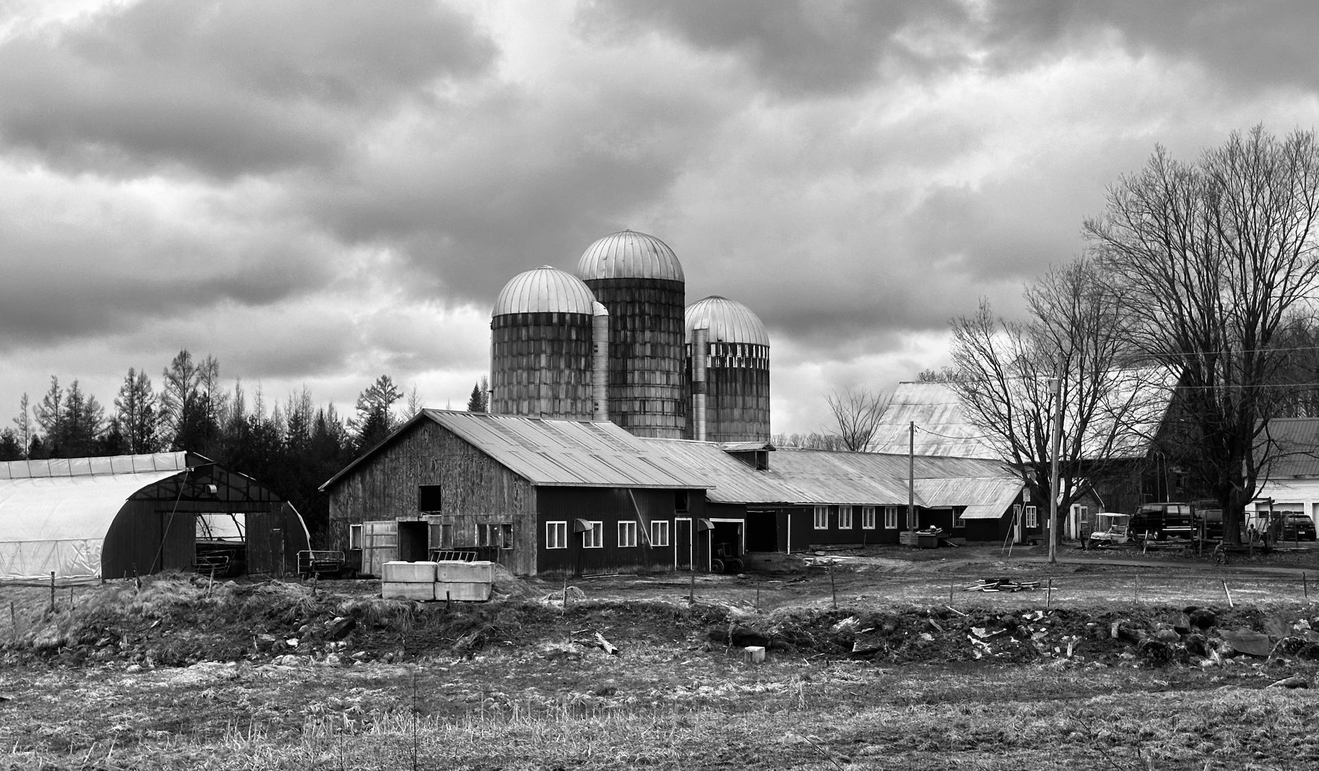 A black and white photo of a farm with silos in the background