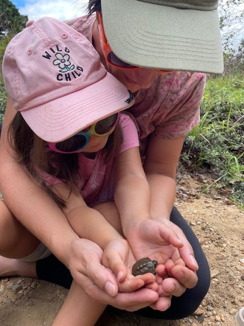 a woman and child are holding a small frog in their hands