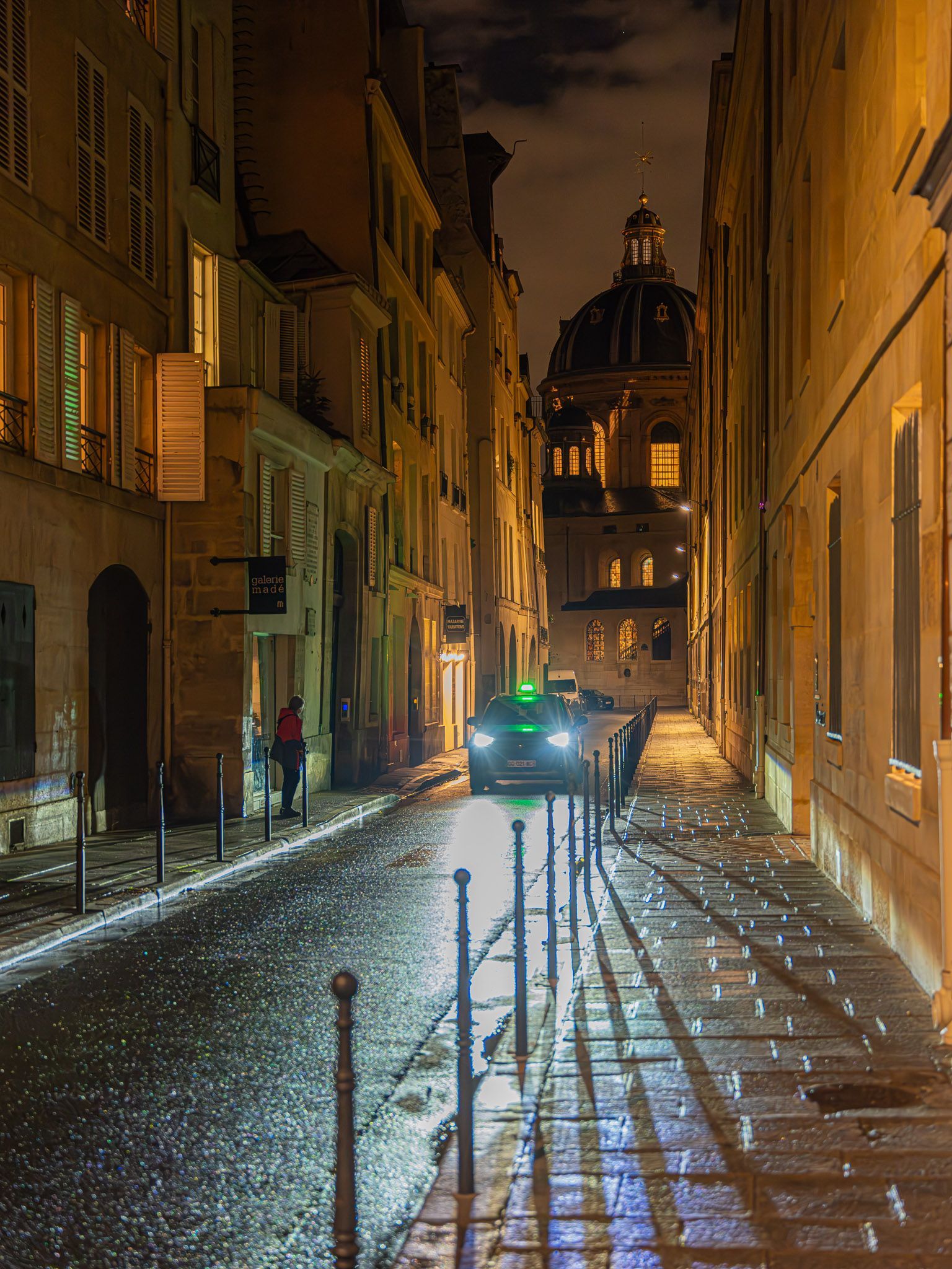 a car is driving down a narrow street at night .
