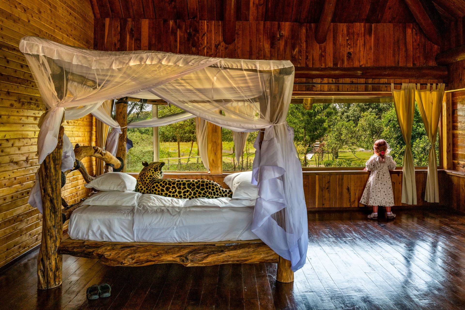 a little girl is standing next to a canopy bed with a leopard on it .