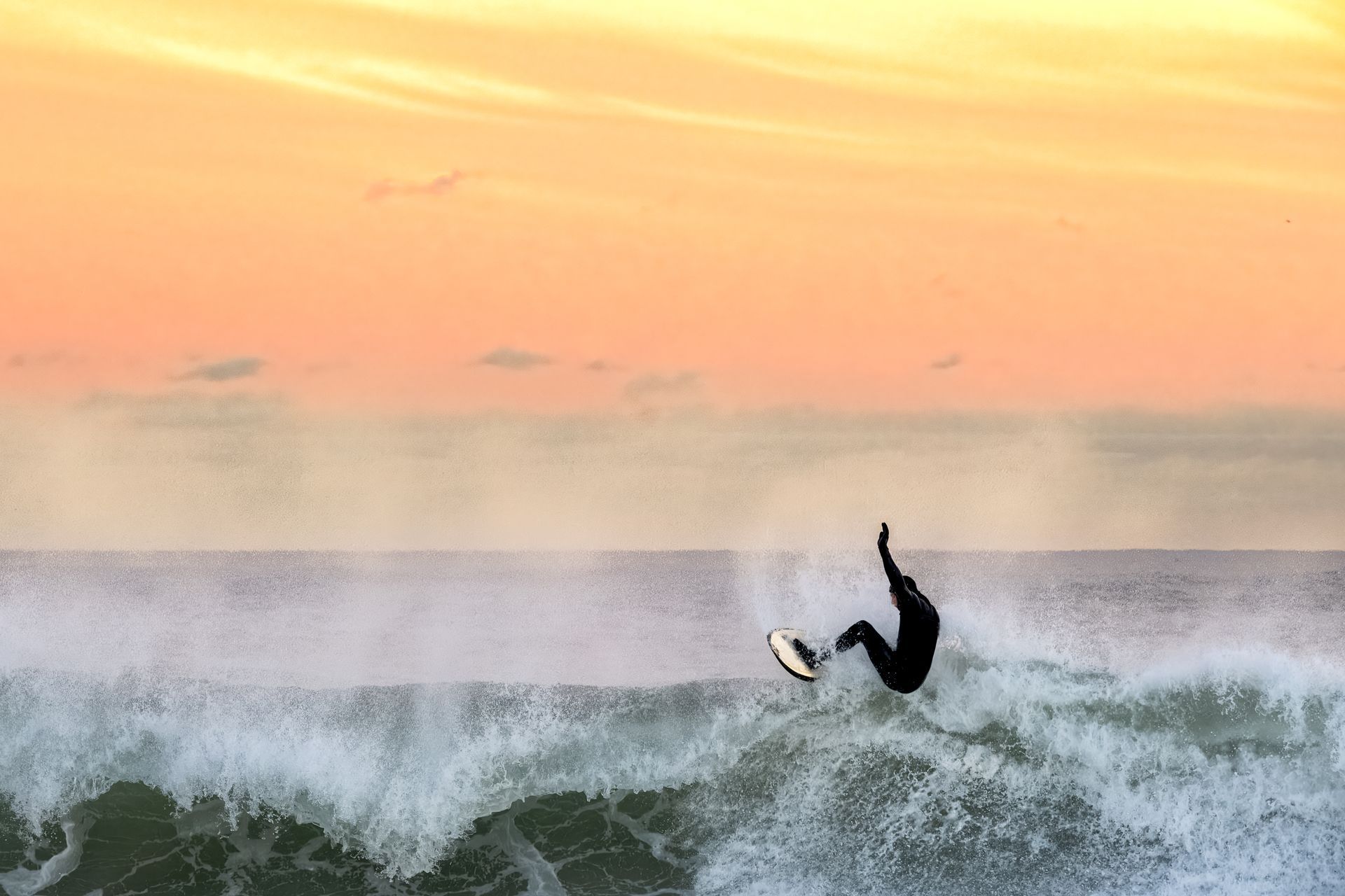 a surfer is riding a wave in the ocean at sunset .
