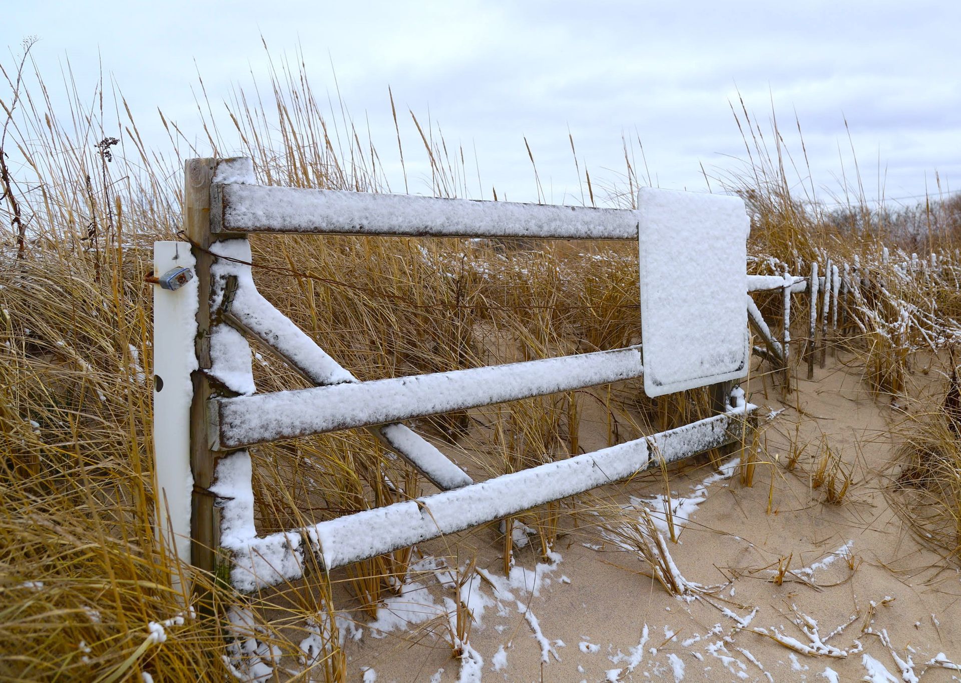 a wooden gate is covered in snow in a field