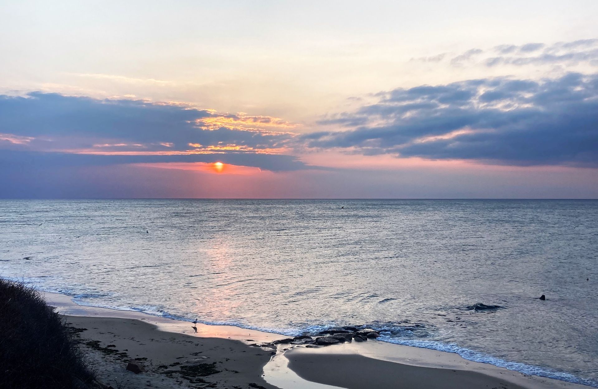 a sunset over the ocean with waves crashing on the beach