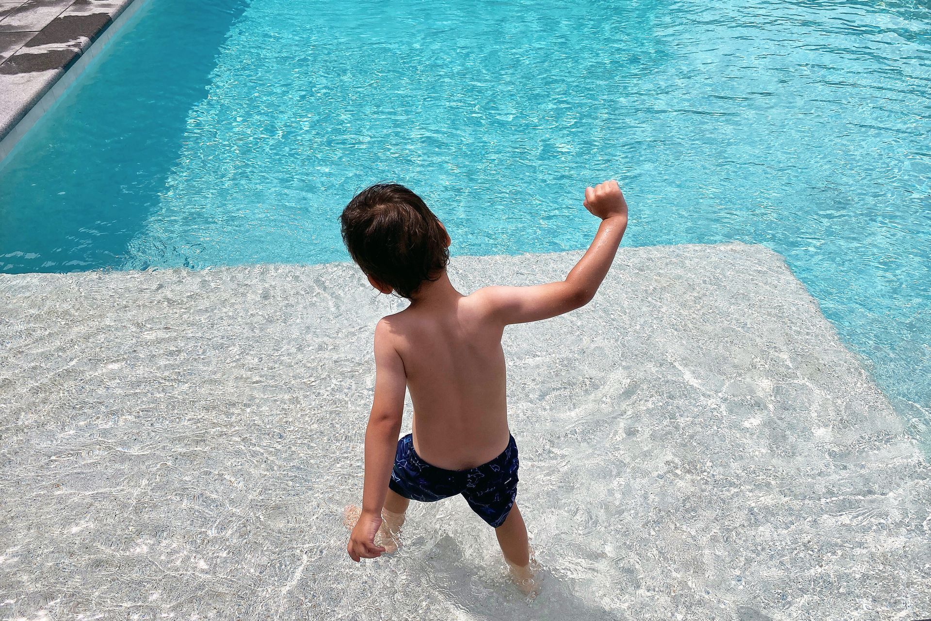 a young boy is standing on the edge of a swimming pool .