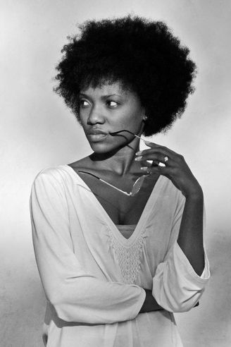 A black and white photo of a woman wearing glasses and a white dress.