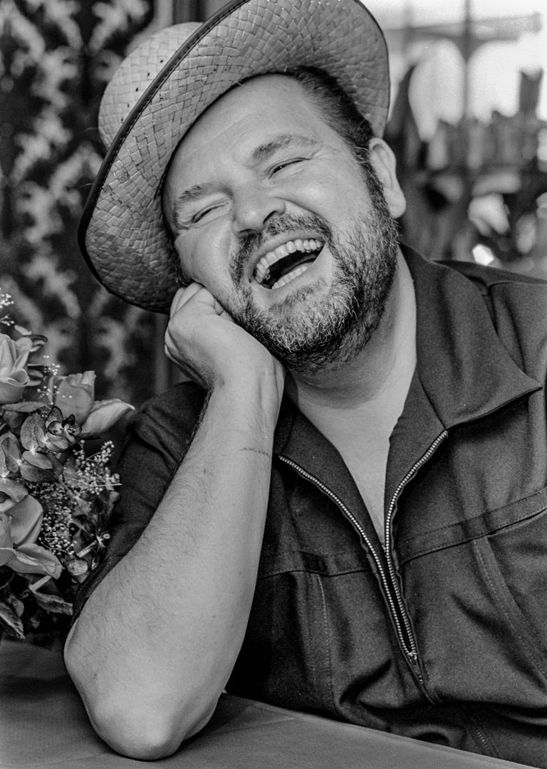 A black and white photo of a man wearing a hat and smiling