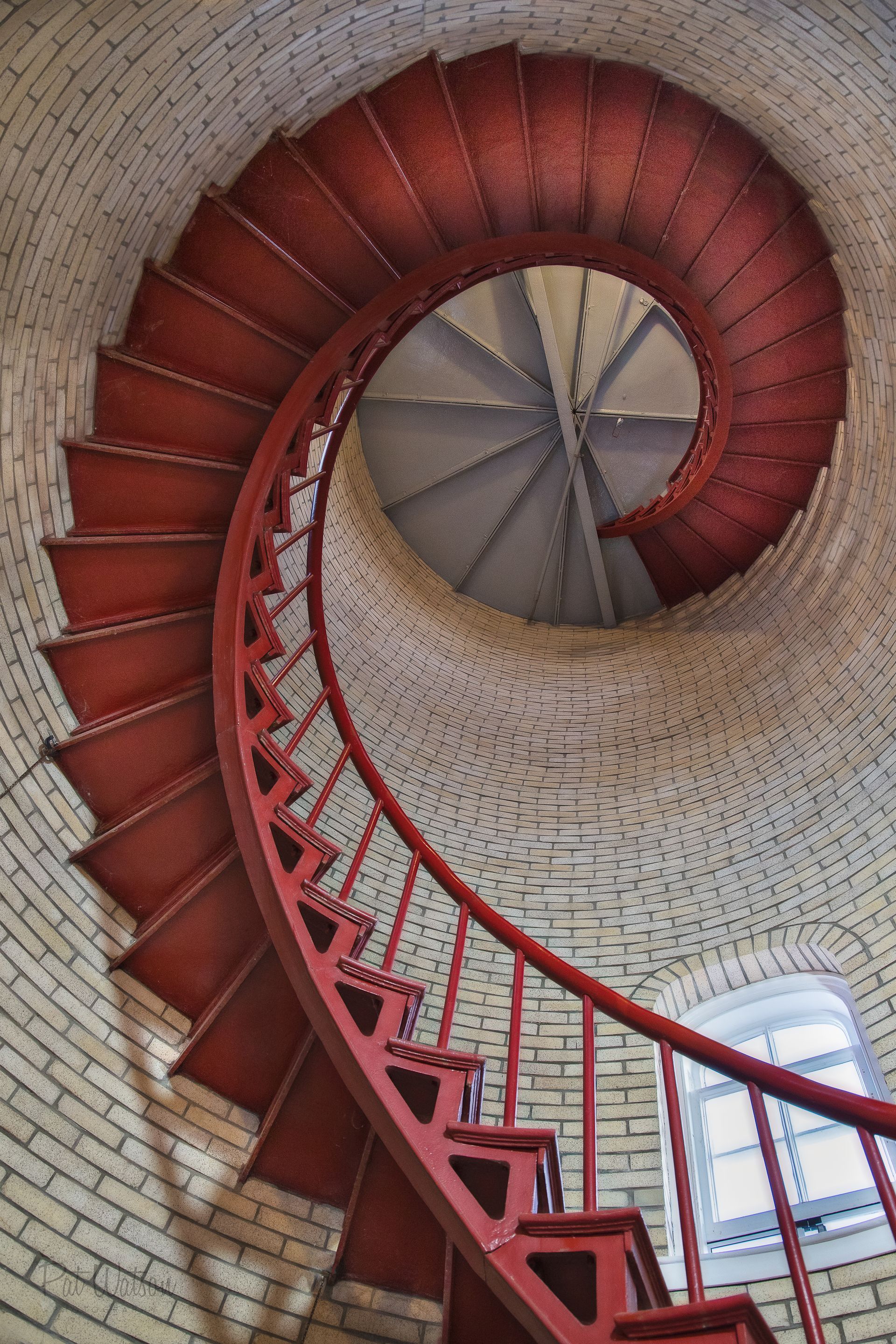 a red spiral staircase is going up a brick tower .