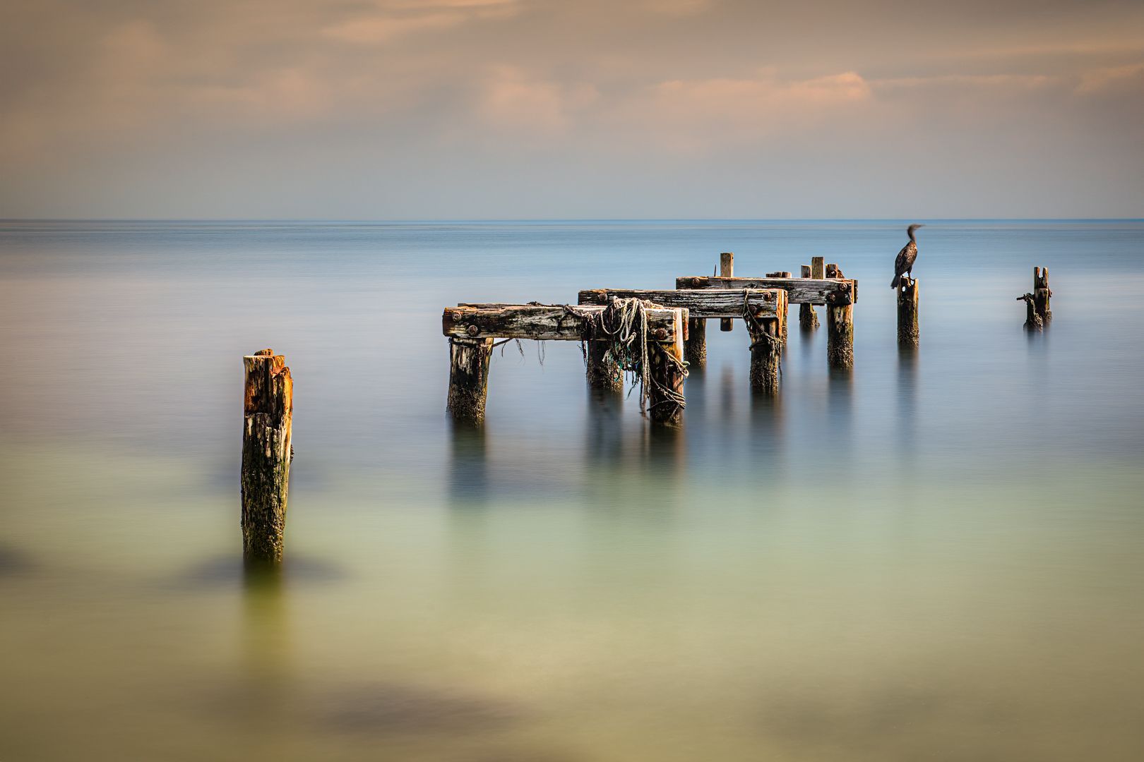 A long exposure photo of a pier in the ocean.