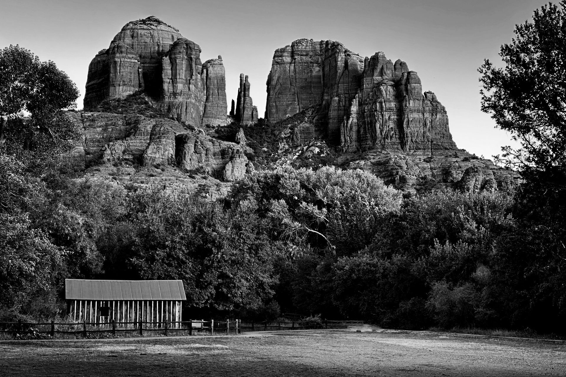 A black and white photo of a mountain with a small building in the foreground