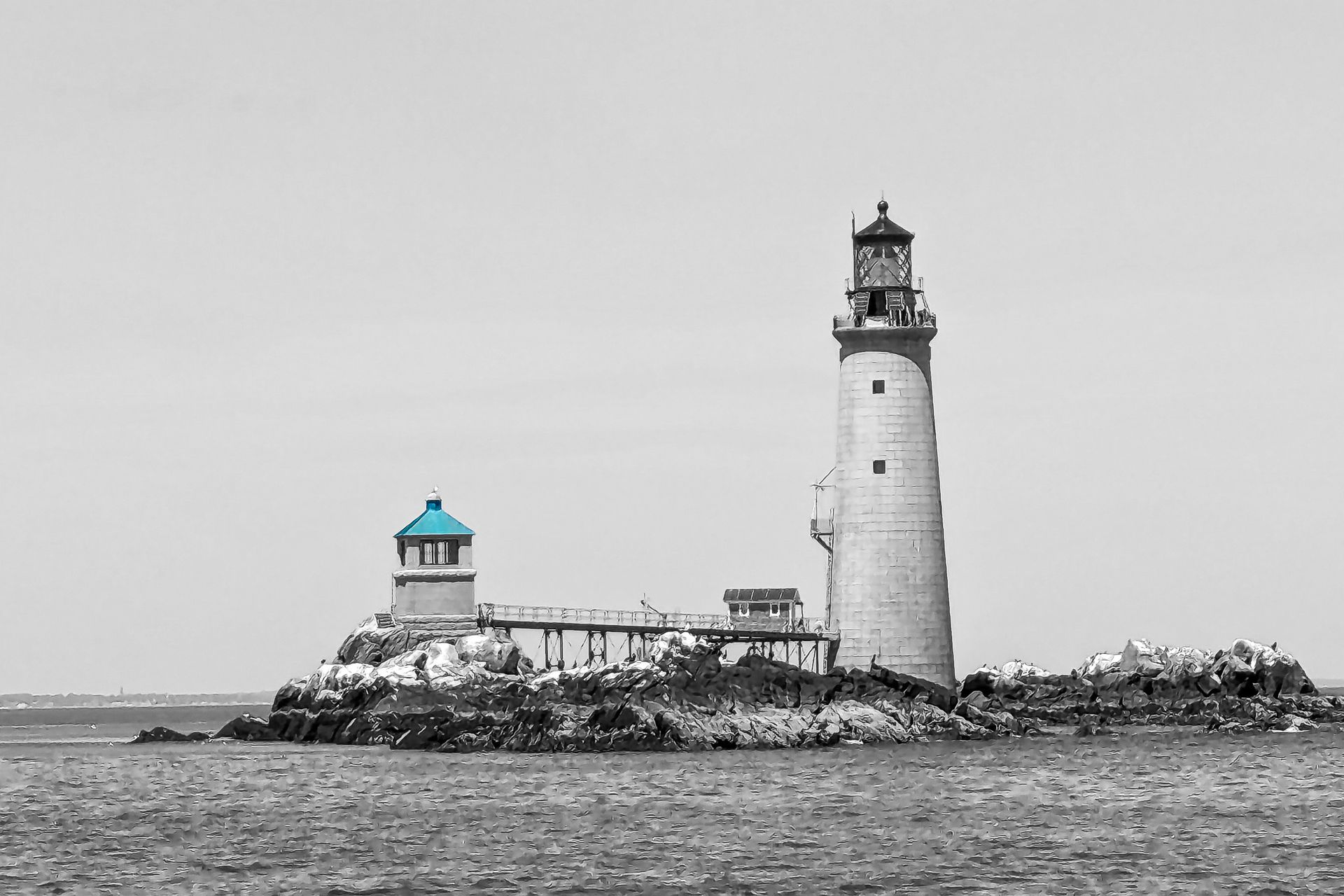 A black and white photo of a lighthouse on a small island in the middle of the ocean.