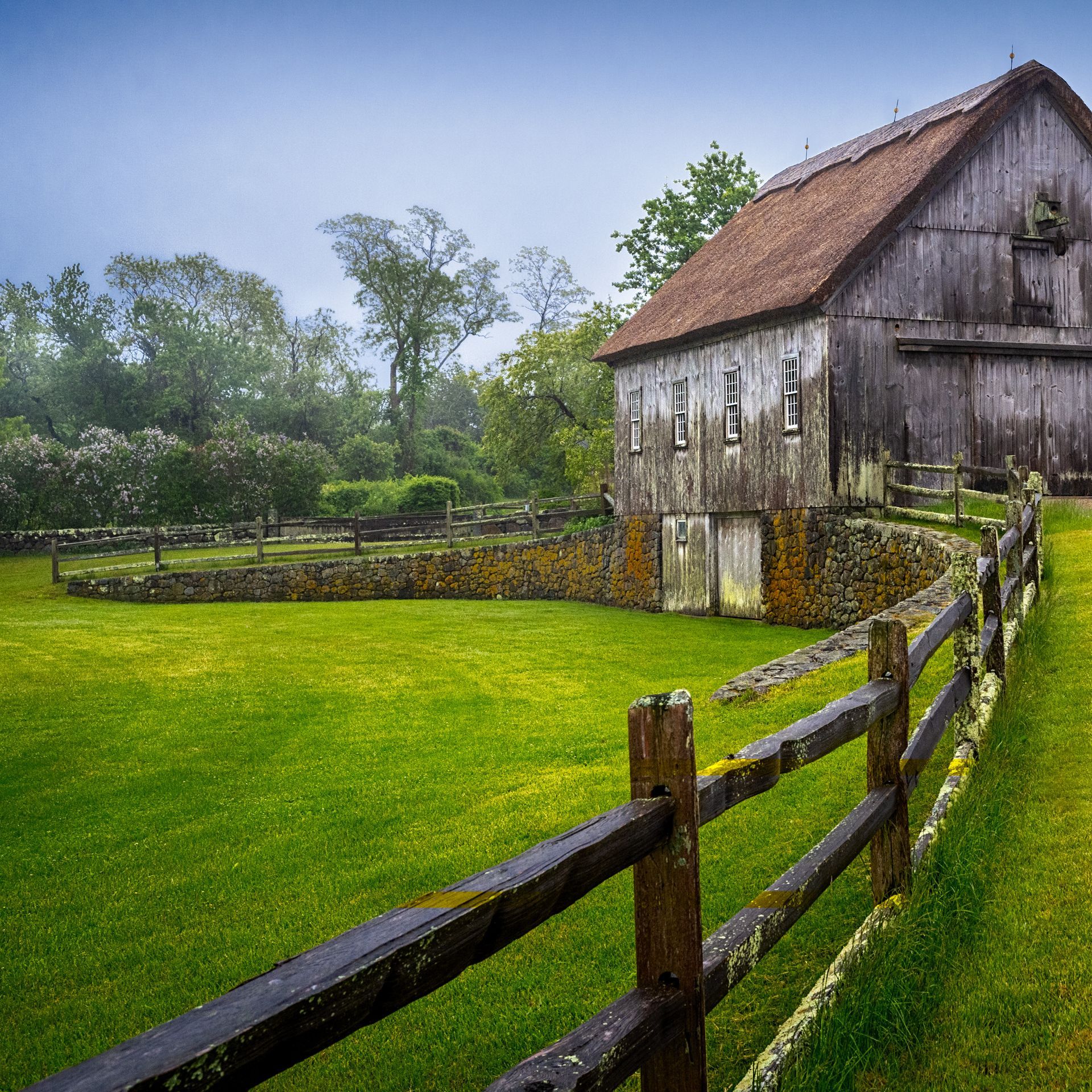 a barn with a wooden fence in front of it
