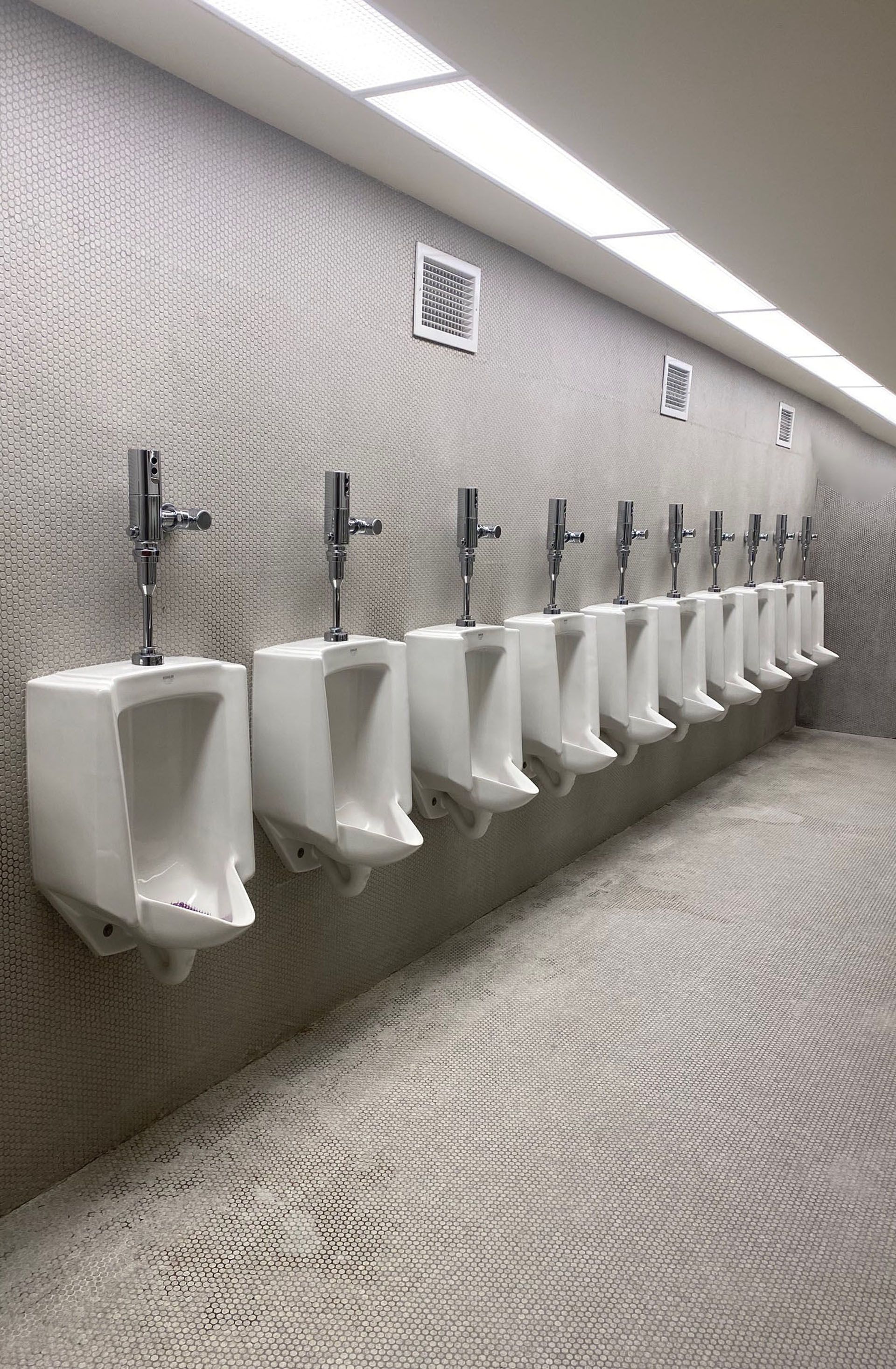 A row of urinals are lined up in a public restroom.