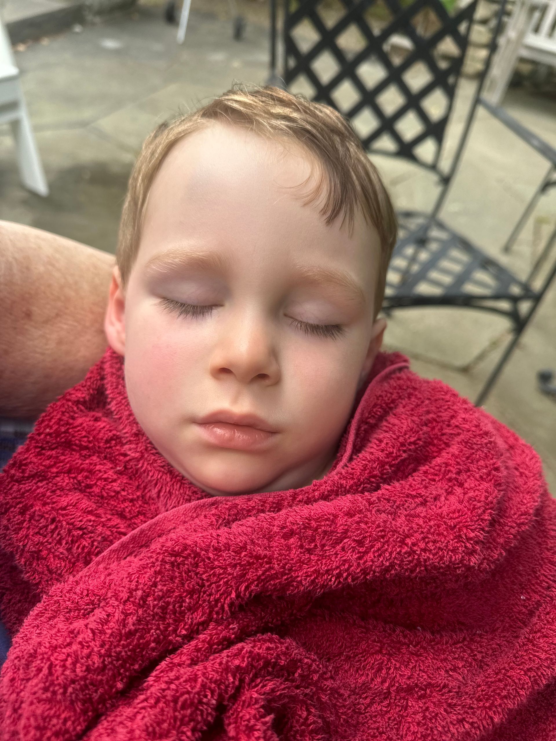 a young boy is wrapped in a red towel and sleeping .