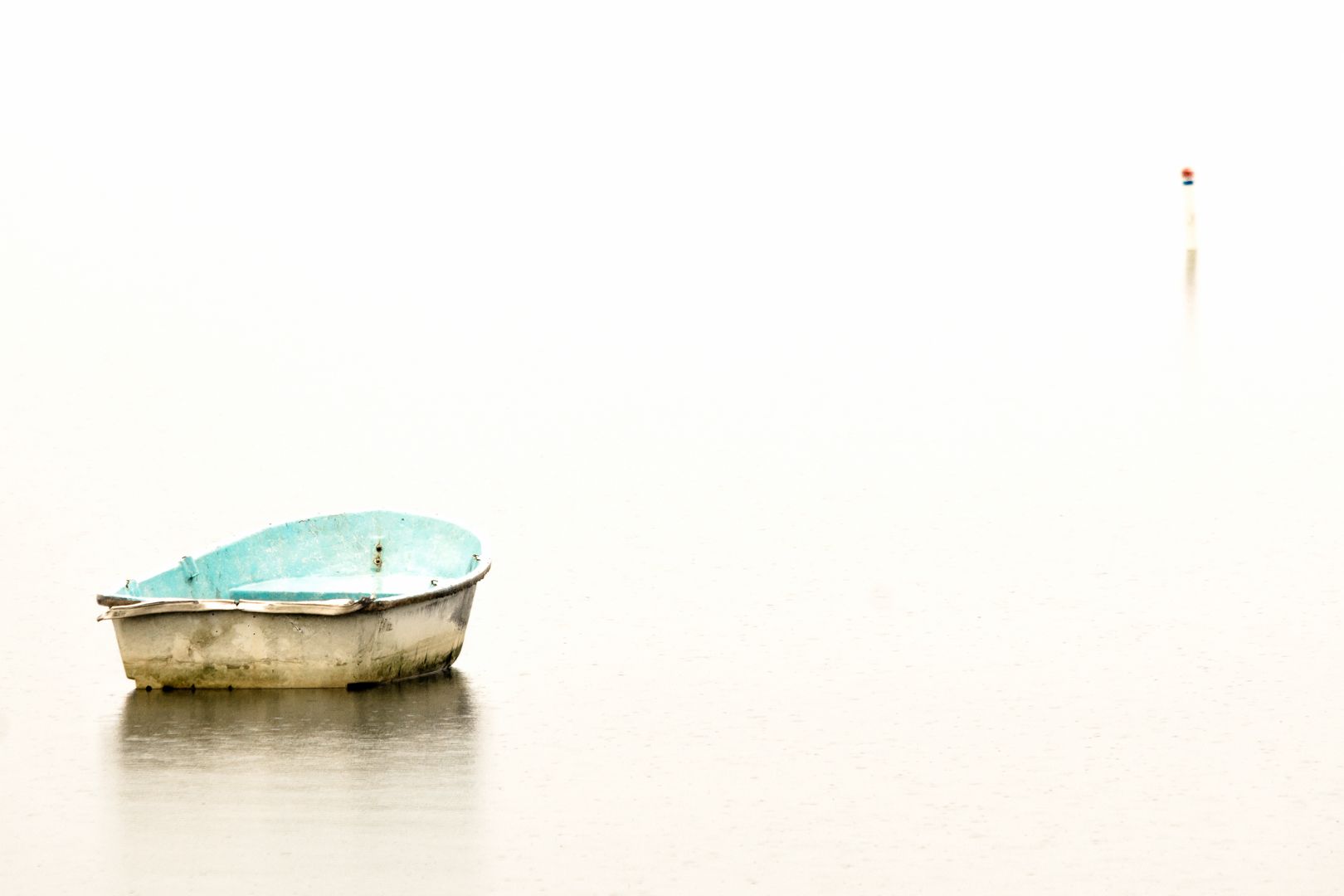 A small blue boat is floating on top of a body of water.