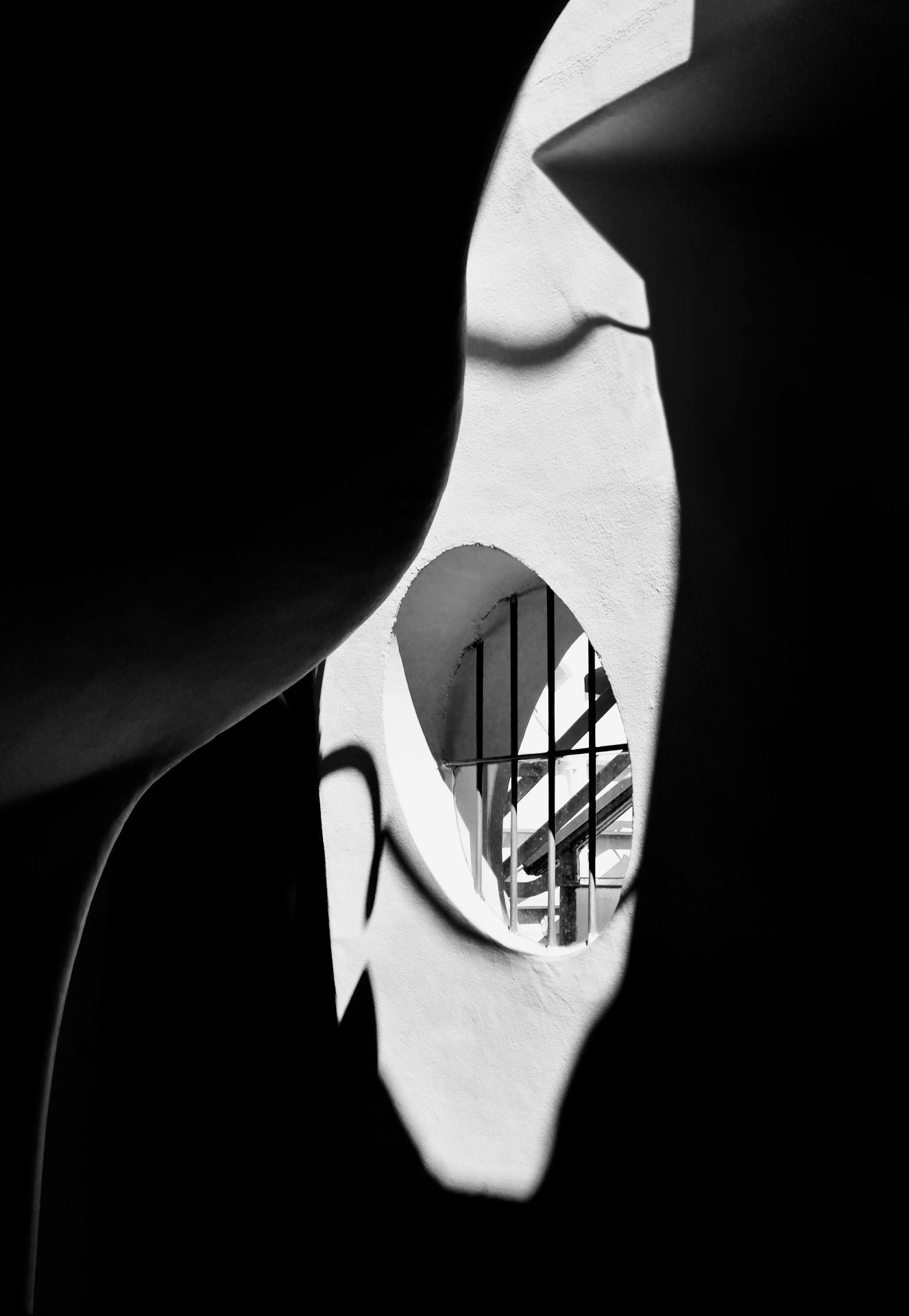 A black and white photo of a building through a hole in a wall