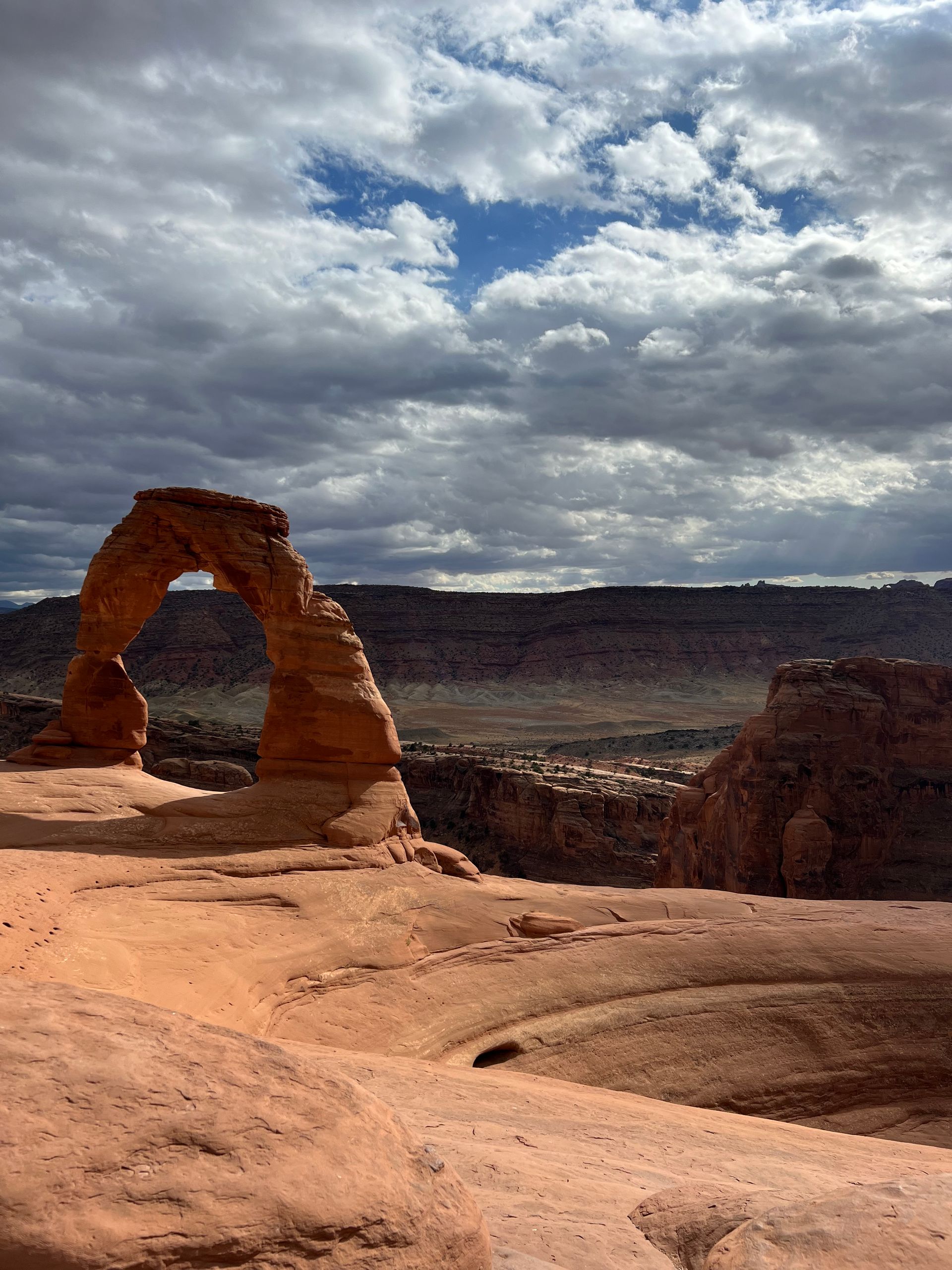 a large rock formation in the middle of a desert with a blue sky and clouds in the background .