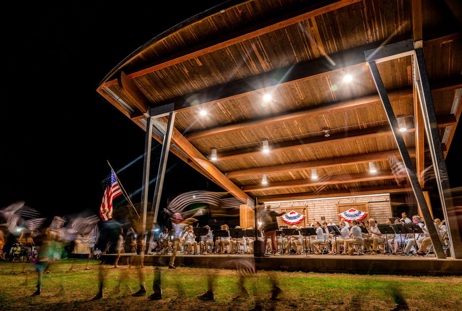 A band is playing under a wooden roof at night.