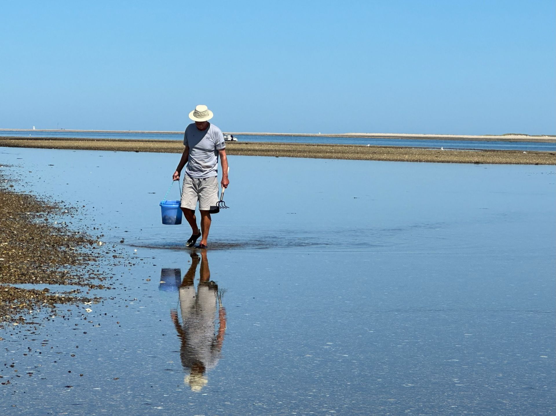 a man is walking through a body of water carrying a bucket