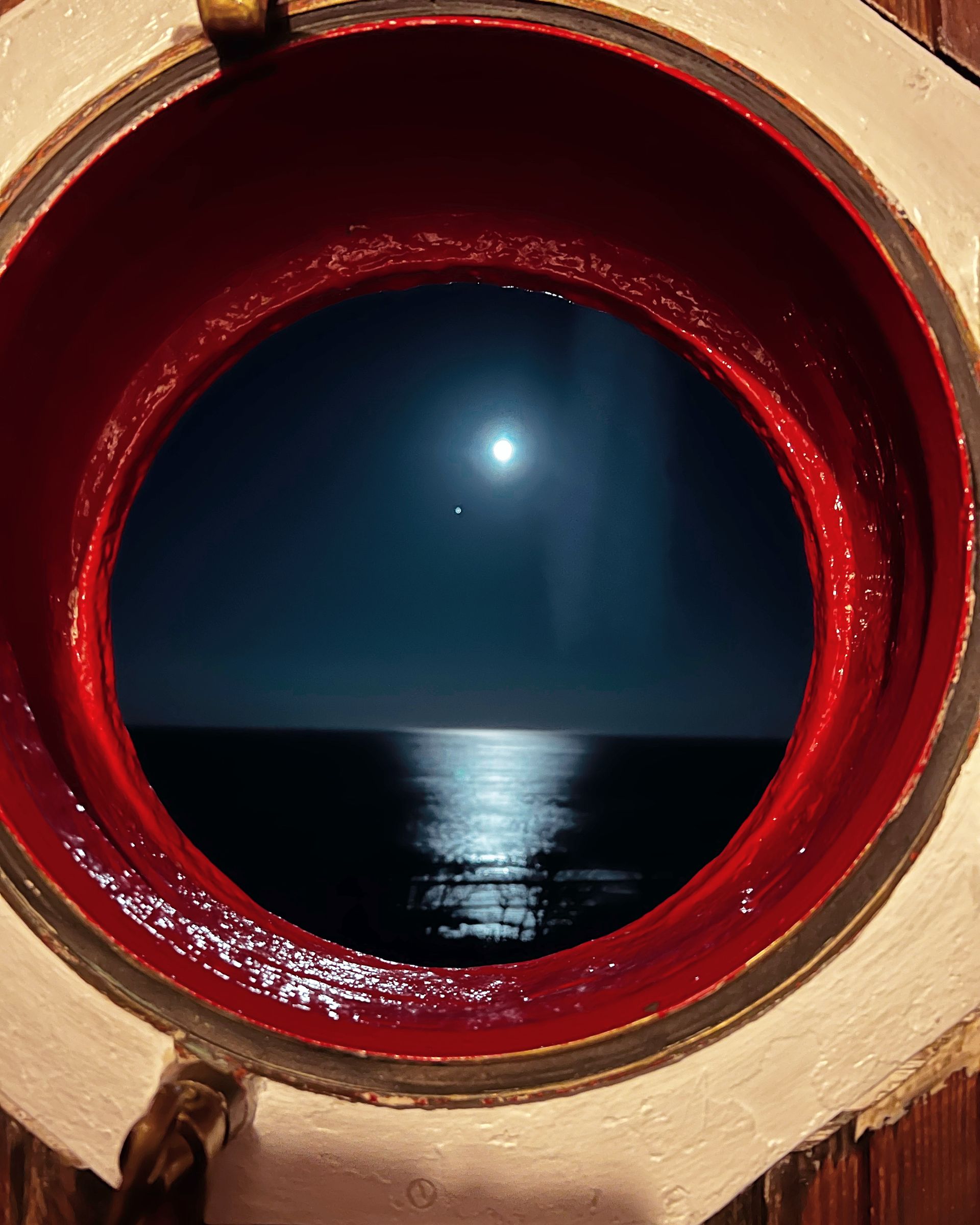 a view of the ocean through a porthole at night