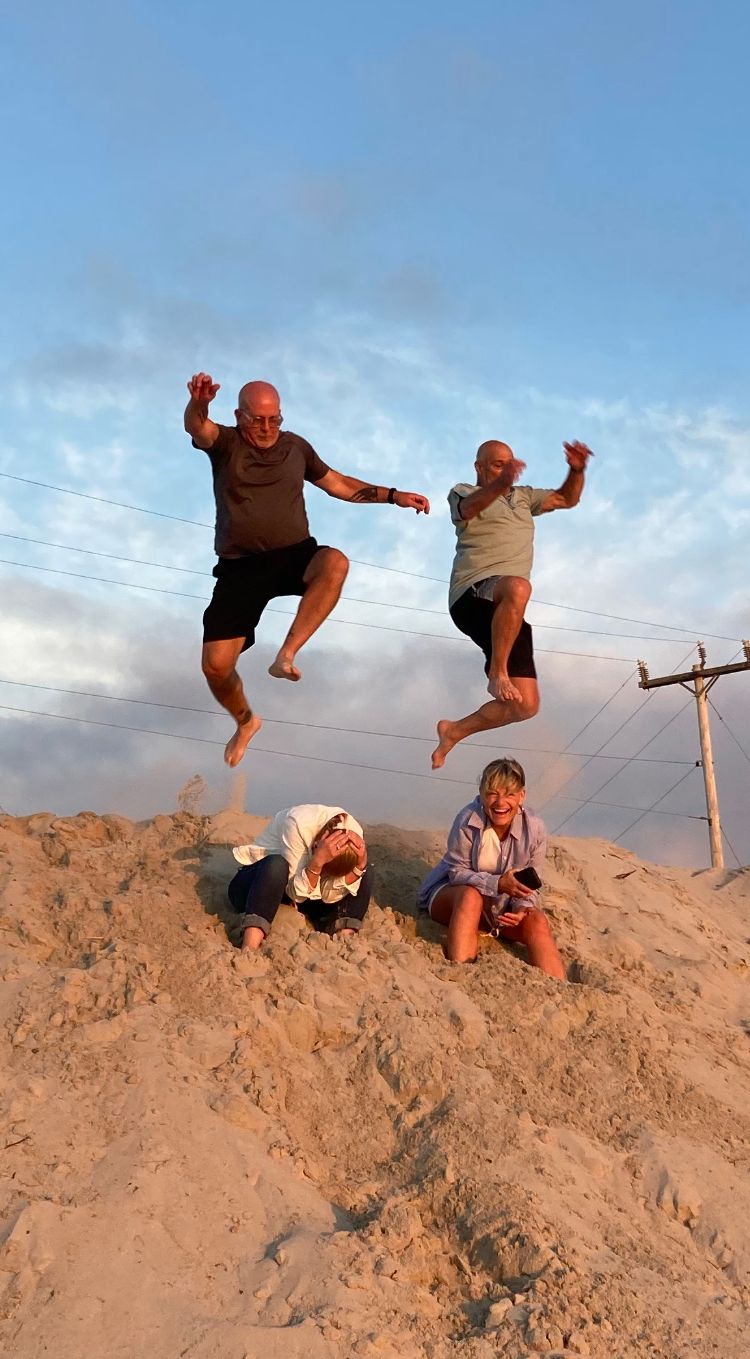 a group of people are jumping in the air on a sandy beach .