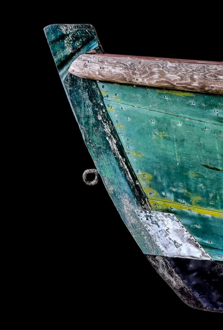 A close up of a green boat on a black background.
