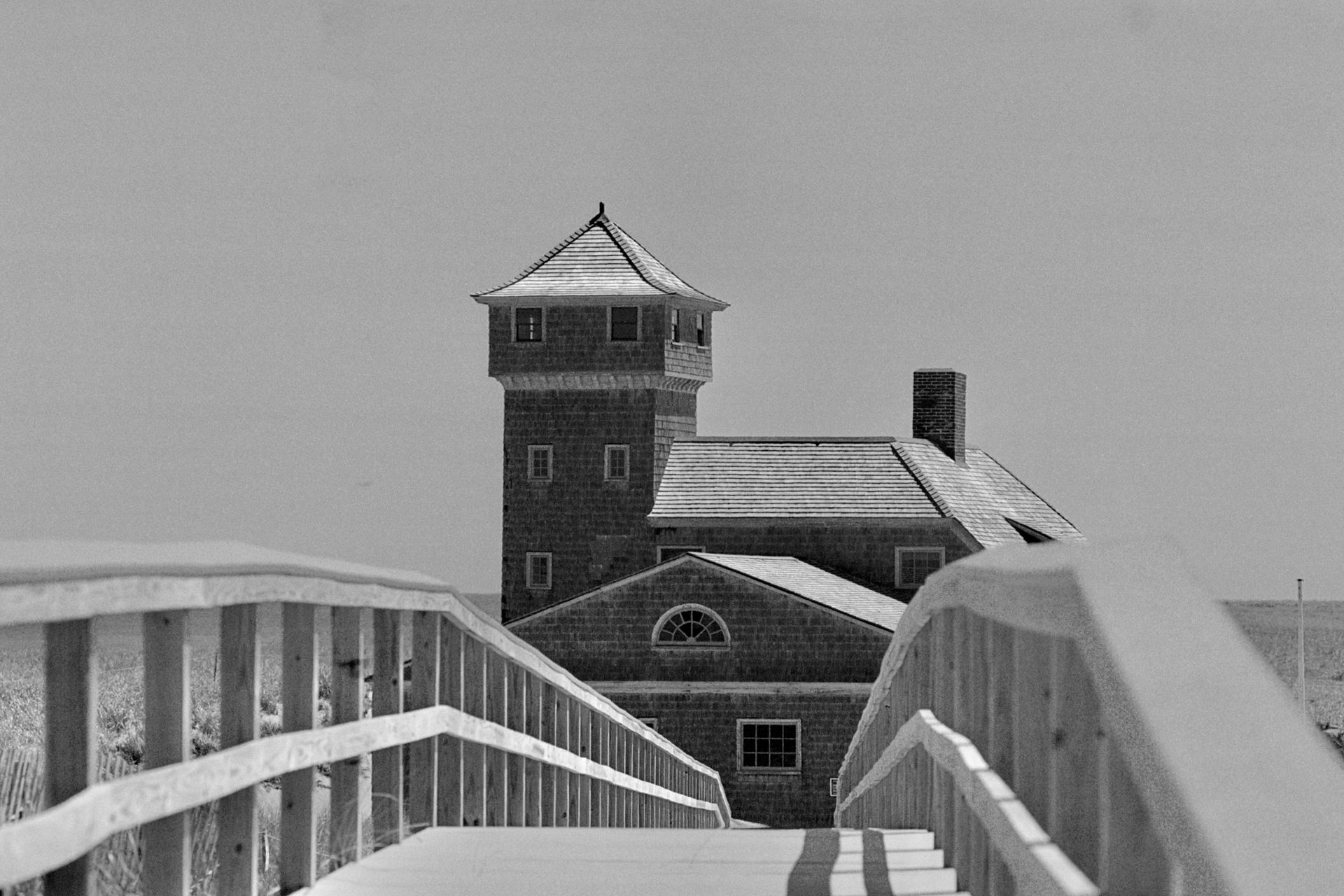 A black and white photo of a bridge leading to a building