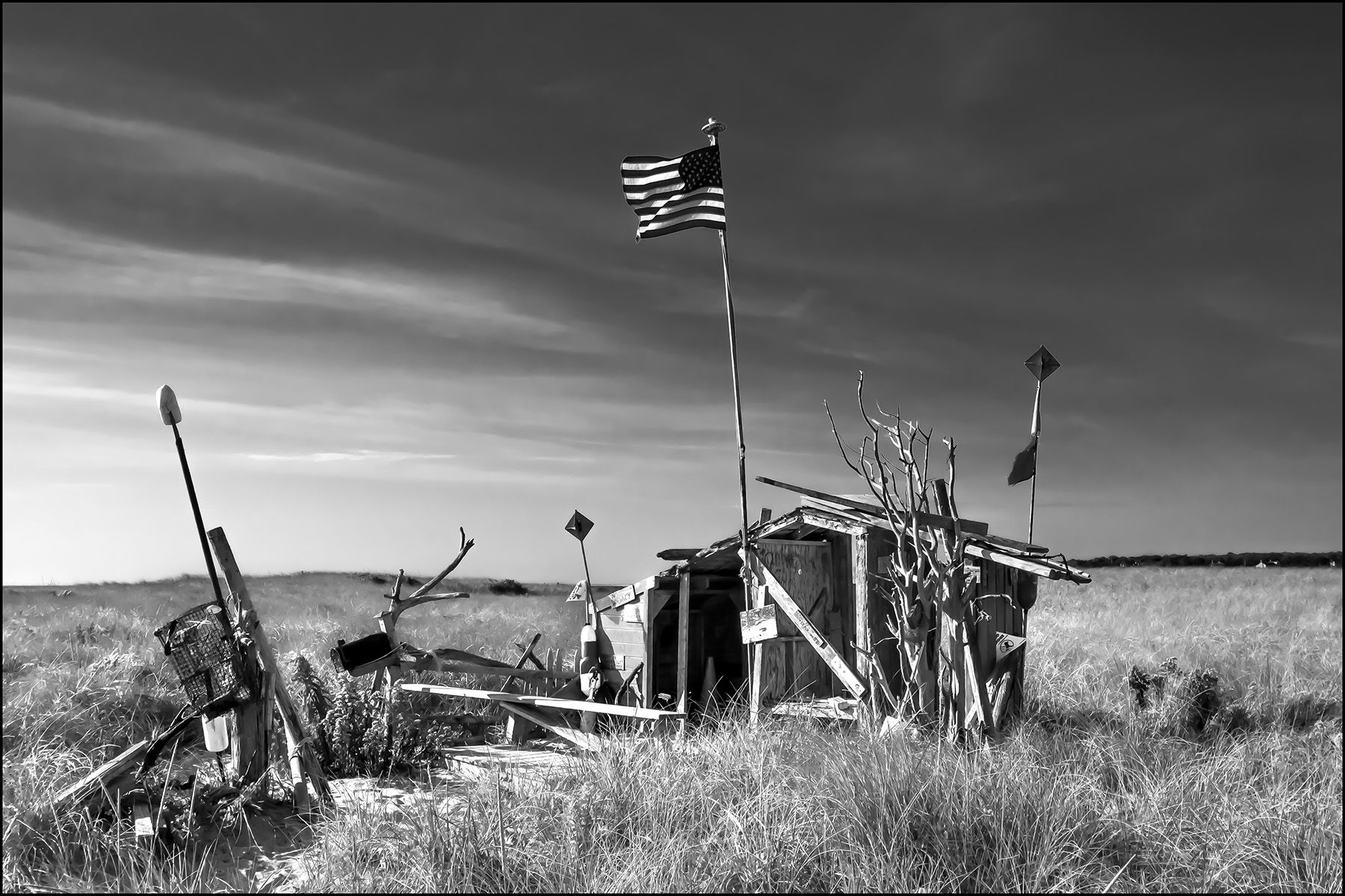 A black and white photo of a shack with an american flag on top