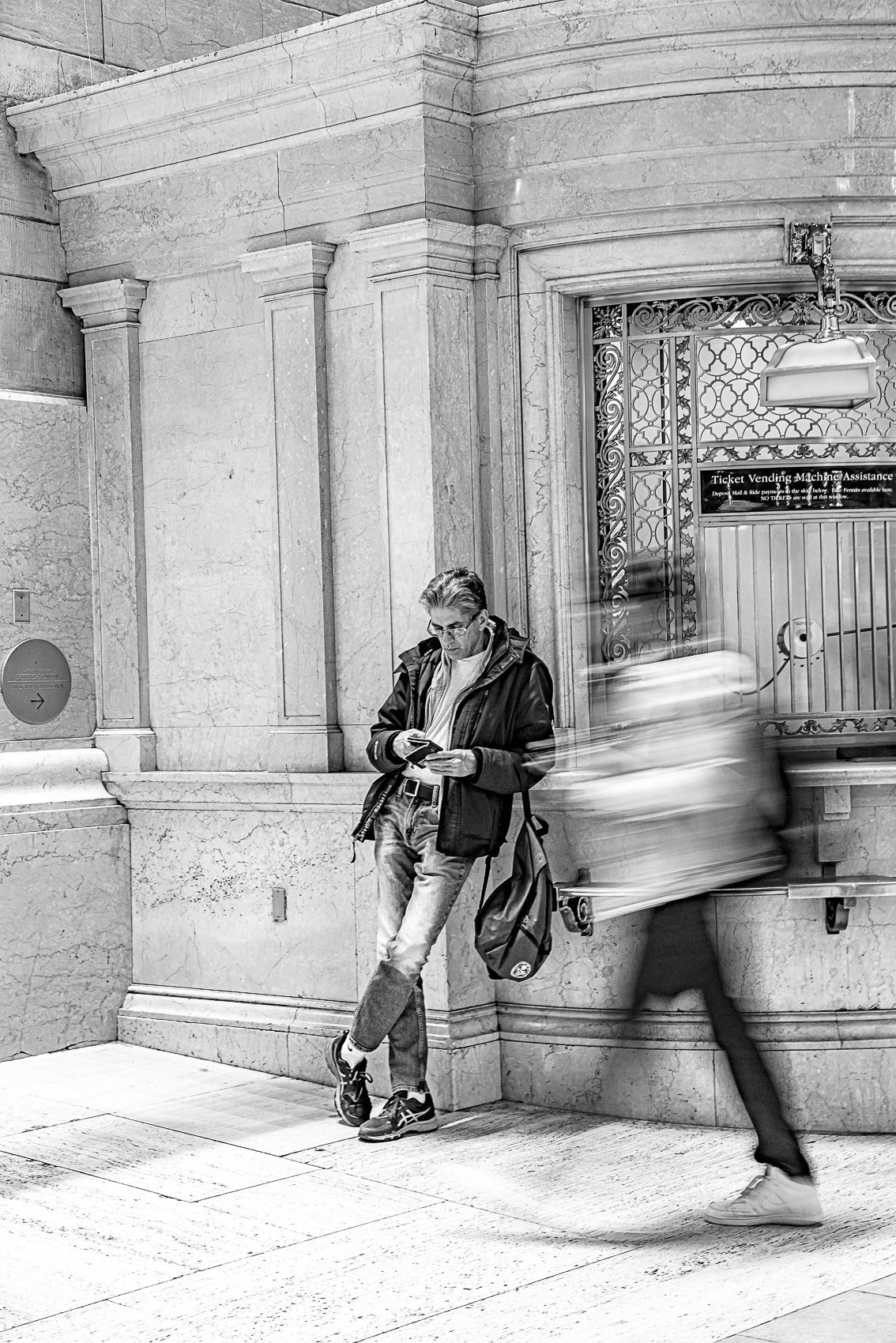 A black and white photo of a woman standing in front of a building.