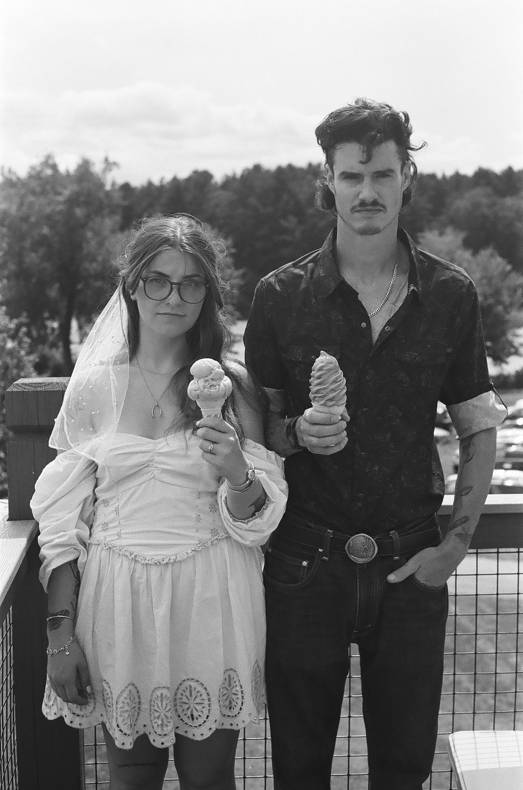A man and a woman are standing next to each other holding ice cream cones.
