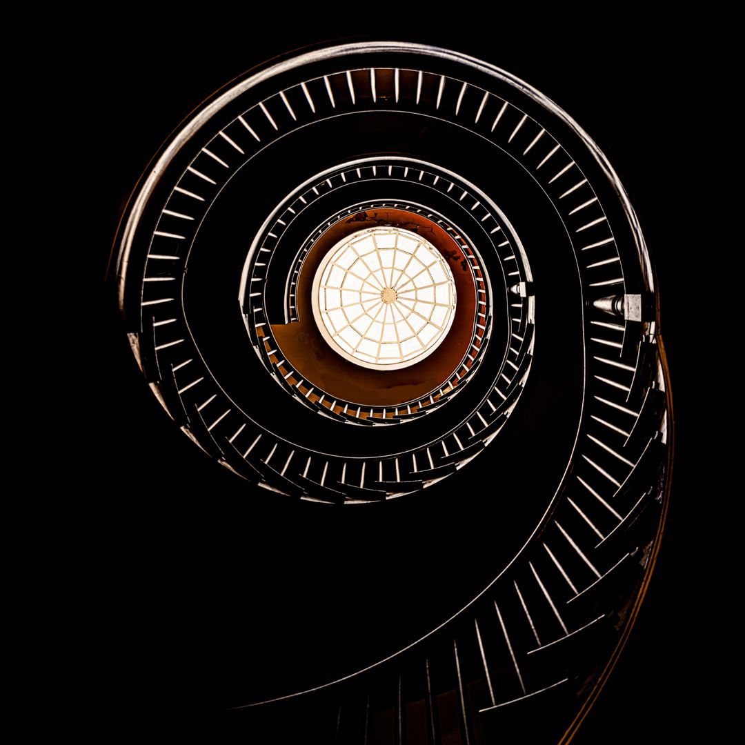 Looking up at a spiral staircase with a light in the middle.